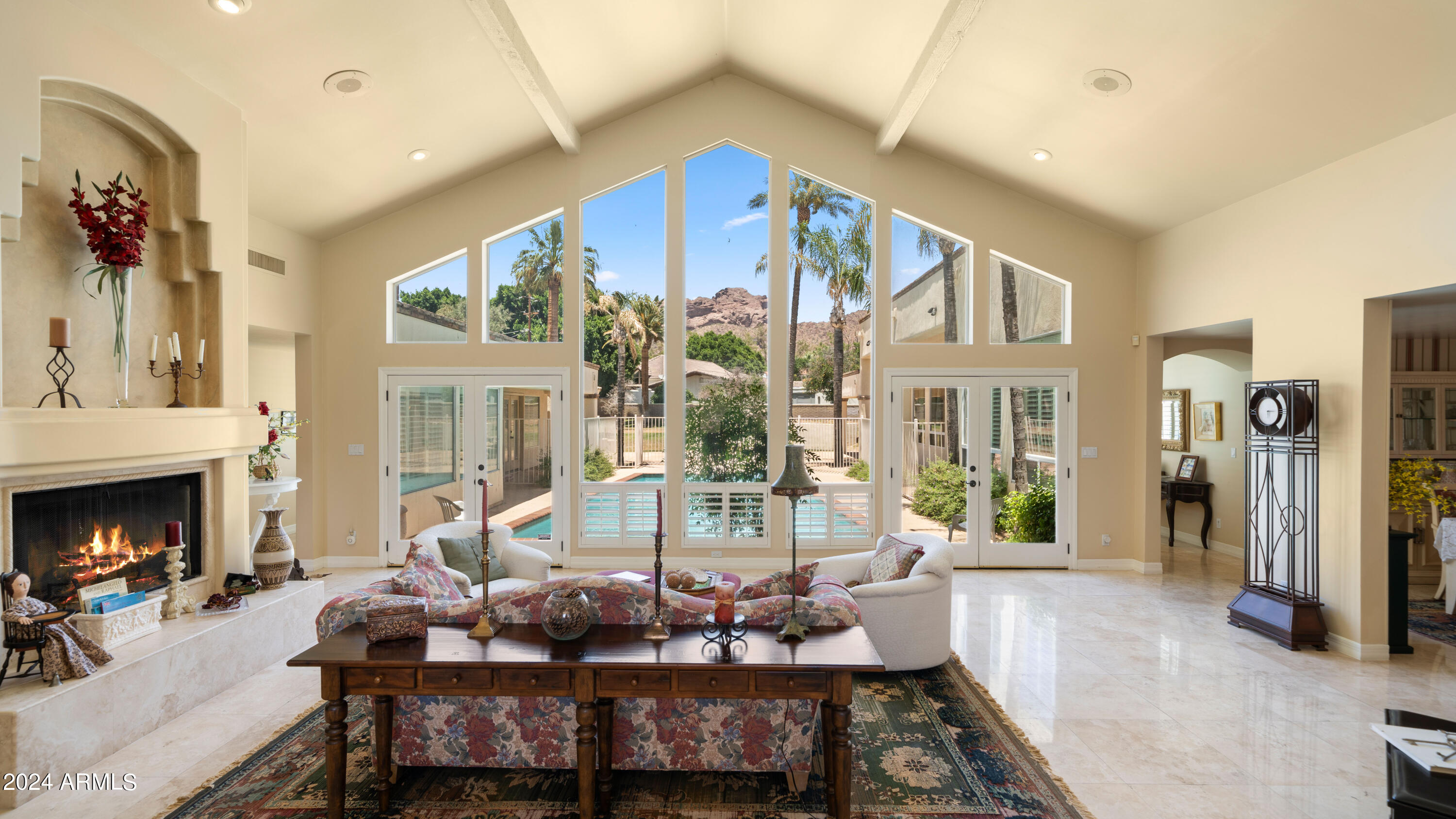 This beautiful Arcadia home has breathtaking views of Camelback Mountain through the 16-foot windows in the living room.  Originally built in 1974, it was remodeled with a large addition in 1990 and partially rebuilt in 2009.  There are five bedrooms and four bathrooms; the master bedroom has cathedral ceilings and is split from a two-bedroom children's wing and two guest rooms.  There are two adjoining family rooms (one could be converted into a sixth bedroom), a library/den, and three fireplaces.  The bedrooms are carpeted and the remainer of the house has travertine flooring.  The kitchen has a large island, granite countertops, an oversized refrigerator and an oversized freezer that are separate units, a beverage counter refrigerator, two microwaves, a double wall oven, a separate cooktop, a warming drawer oven, and a dishwasher.  The kitchen has a large separate eating area and there is also a separate dining room.  The home is U-shaped and surrounds the pool.  Outside there is a ramada, a porch, a fountain, and a lighted sports court.