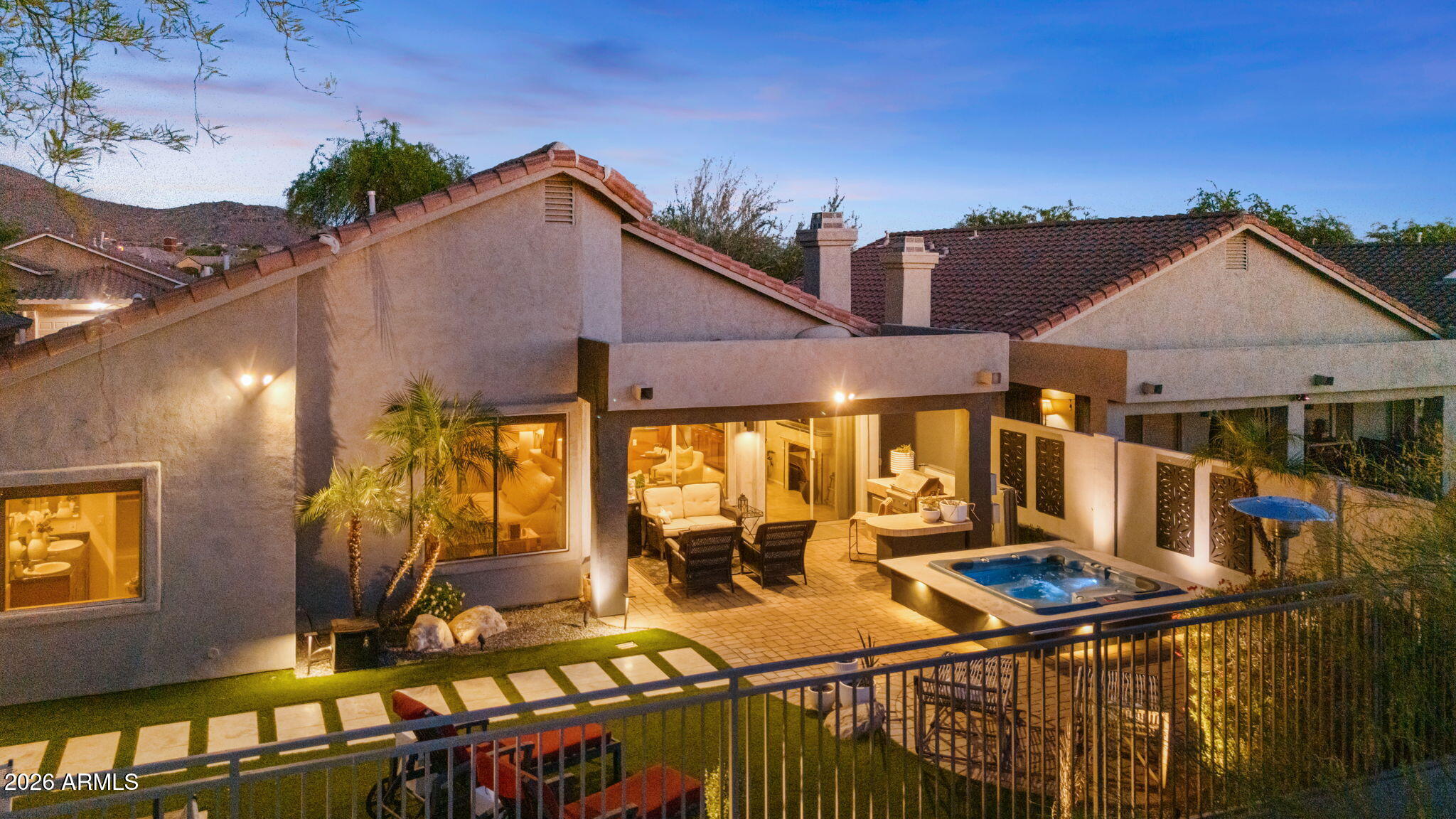Available June 6th! Beautifully updated open-concept home with soaring ceilings, spacious living and family rooms, and elegant finishes throughout. The chef's kitchen features a remodeled oversized extended island, additional cabinetry and built-in wine refrigerator, perfect for entertaining. The primary suite includes an ensuite bath and walk-in closet with Classy wash  Closets built-ins. Upgrades include RO water system, water softener, tankless water heater, automated blackout blinds, newer AC, app-controlled Trane thermostat and three 75''-85'' TVs. The remodeled backyard features stucco-finished walls, Jacuzzi, synthetic grass, travertine and outdoor fireplace with grill/bar area. Enjoy the privacy of this resort style home situated on a wash with mountain views