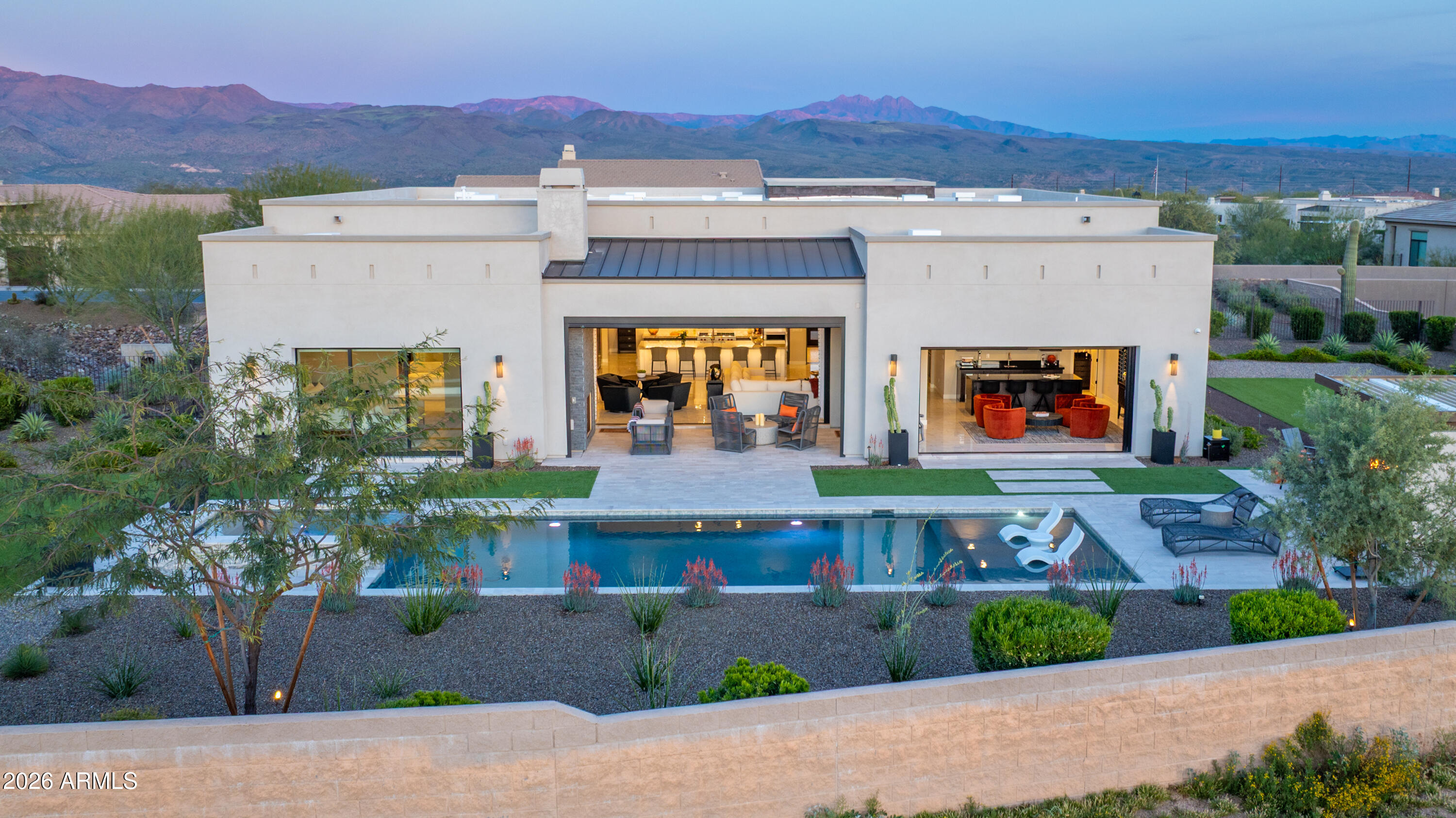 A Desert Modern Masterpiece awaits in the remarkable 24-hour guard-gated community of Trilogy at Verde River. This Toll Brothers home was designed as both a retreat and a statement, offering over $900,000 in curated upgrades and intentional design. A striking entry welcomes you into a soaring foyer crowned by a 14-foot ceiling. Every finish has been intentionally crafted to create an atmosphere of calm sophistication. The great room serves as the heart of the home, framed by 14-foot ceilings and expansive sliding glass doors that seamlessly connect indoor living to the serene desert backdrop. The open-concept design flows into a chef's kitchen anchored by a dramatic granite waterfall island. A professional-grade appliance suite from Sub-Zero and Wolf includes dual dishwashers, while a built-in coffee bar, wine refrigeration, and a butler's pantry elevate both everyday living and large-scale gatherings. For more intimate settings, a dedicated bonus room with a built-in bar offers the perfect atmosphere for evening cocktails and conversation. 

The primary suite is a private sanctuary featuring dual illuminated vanities, a freestanding soaking tub, and a glass-enclosed shower. The custom walk-in closet provides exceptional organization. The home offers two generously appointed guest bedroom suites that provide comfort and versatility, complemented by a separate executive home office with glass French doors offering both privacy and natural light. Guests enjoy their own refined retreat in the attached casita, which offers a private exterior entrance from the courtyard for comfort and discretion. Throughout the home, you will find electronic silhouette shades by Hunter Douglas and designer lighting. 

Positioned on a 24,500-square-foot homesite, the backyard is a $550,000+ resort-caliber landscape designed by Creative Environments. This outdoor oasis features a heated saltwater pool and spa, a bocce ball court, and a covered patio anchored by a statement fireplace and Havana electric shades. A fully equipped outdoor kitchen with a professional grill and smoker invites effortless al fresco dining. As the sun sets, the horizon softens to hues reminiscent of chilled rosé, with blush tones stretching across the desert sky. From the epoxy-finished three-car garage with a Tesla EV charger to advanced water filtration systems, every element of this residence reflects a seamless union of luxury, innovation, and intentional living.

Life at Trilogy at Verde River is anything but ordinary. Challenge yourself on the Tom Lehman 18-hole golf course, the dedicated pickleball and tennis courts, or the professional bocce ball courts before relaxing in the resort-style pools and hot tub. Power up at the Afterburn Fitness Center or get creative in Helen's Demonstration Kitchen and the Art Loft. While your pups roam the 7.5-acre dog park, you can savor everything from casual bites at Eddy's Diner to sophisticated flavors at Needle Rock Kitchen & Tap. With Alvea Spa on-site and the majestic Tonto National Forest trails just beyond your doorstep, every day is a perfect blend of adventure and indulgence.