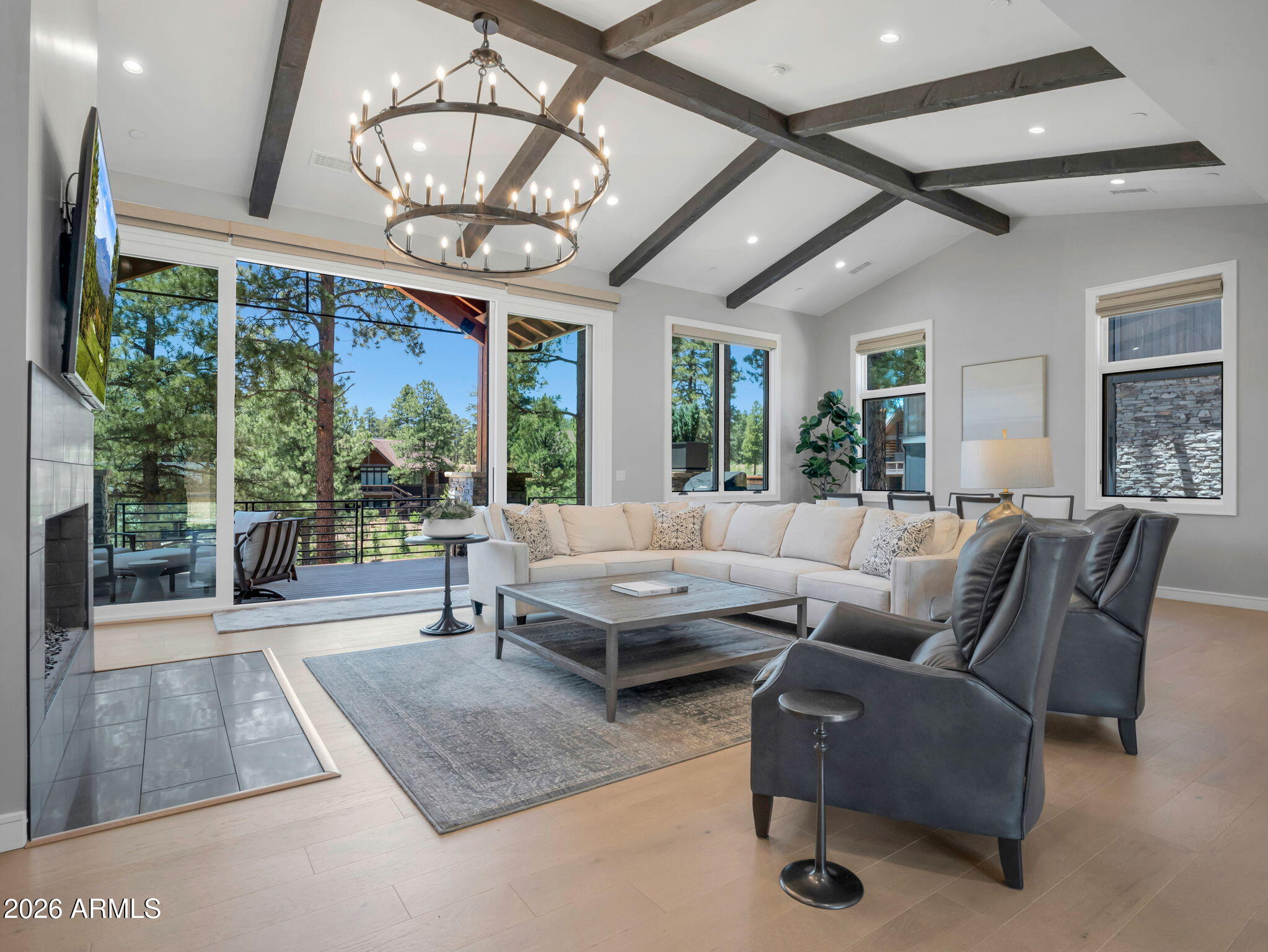 This beautifully appointed 3 bedroom, 3.5 bathroom single family home in Pine Canyon's desirable Coconino Ridge neighborhood offers 3,792 square feet of thoughtfully designed living space surrounded by the beauty of the Ponderosa pines. Warm wood tones, clean architectural lines, and expansive windows create a refined mountain retreat that feels both sophisticated and inviting. The main level is designed for effortless everyday living and entertaining, with an open-concept great room highlighted by vaulted ceilings, exposed beams, a statement fireplace, and expansive glass doors that frame the forest setting. The adjoining kitchen features custom cabinetry, quartz countertops, premium appliances, and a generous center island, flowing seamlessly into the dining and living areas.
Step outside to the spacious covered deck, where a built-in barbecue creates the perfect setting for outdoor dining and entertaining while enjoying views toward the Flagstaff Urban Trails System (FUTS). The primary suite offers a peaceful retreat with a spa-inspired bath featuring dual vanities, separate shower, and a freestanding soaking tub.
The walkout lower level expands the home's living and entertaining space with a secondary family room, additional guest accommodations, and direct access to a covered patio overlooking the surrounding pines. With multiple indoor and outdoor gathering spaces, generous bedroom suites, and convenient access to the FUTS trail system, this Coconino Ridge residence captures the relaxed sophistication of the Pine Canyon lifestyle.