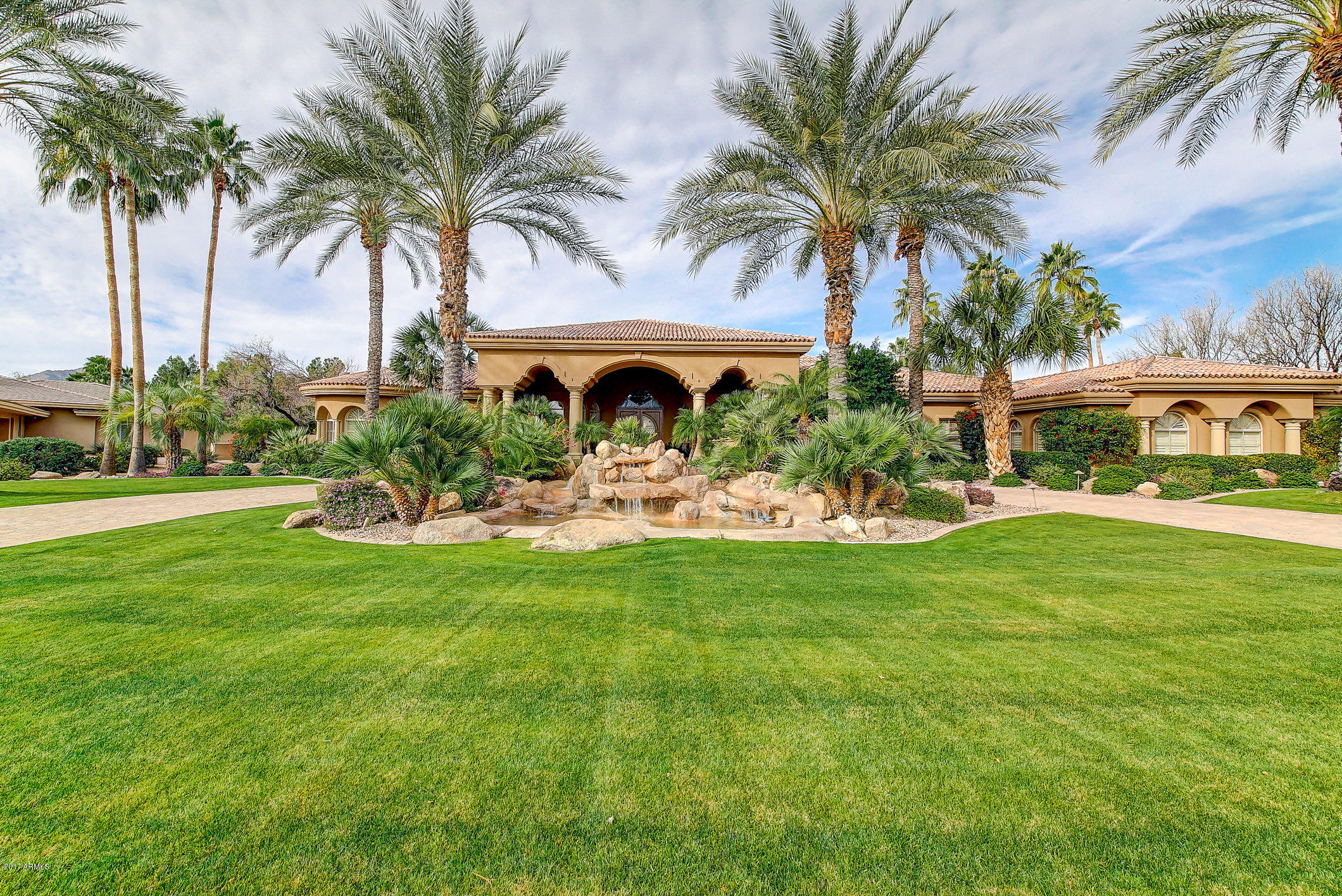 This luxurious resort style home is full of surprises. The curb appeal is spectacular. Located in a gated community with plenty of privacy. Walking through the front door, your view takes you past the living room to the spa/pool and ramada.  Two waterfalls surround the cabana and connect by a meandering waterway. The boulder fire pit and bocce court/ putting green enhance this stunning backyard. A spacious two bedroom guest house was also added to the property. If you like to entertain then look no further. The floor plan gives you plenty of options for any lifestyle. Don't miss out on this hidden gem in Paradise Valley.