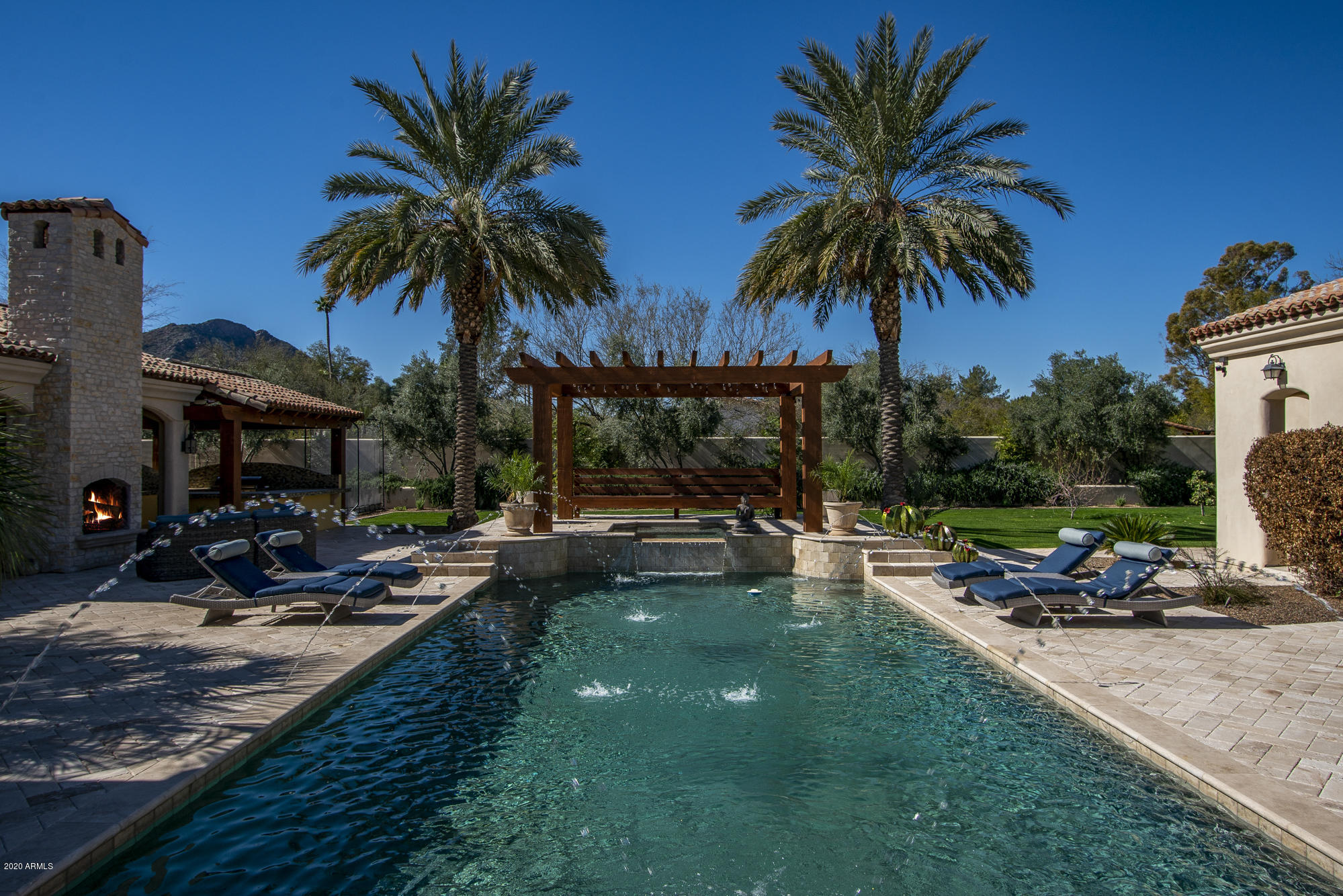 Welcome to this Santa Barbara custom stunner in the heart of PV with gorgeous Camelback Mtn views!  This 1 level beauty features a fabulous open floor plan w/ soaring high ceilings & an over the top resort style backyard with a huge pebble-tech finished pool & spa & multiple deck jet water features, 2 ramadas & built in BBQ. & sport court!  Additionally this amazing gated estate has a separate full sized guest casita for the privacy & comfort of your guests! The oversized chef's kitchen features custom cabinetry, designer granite slab countertops, 2 stunning crystal chandeliers, and an over the top Sub-Zero/Wolf/Asko appliance package! This dream come true kitchen opens to a huge great room that features custom cabinetry & gas fireplace and custom stone flooring.  This light, bright, airy custom estate features 5 bedrooms/5.5 baths, a separate office and a separate theatre room in the main house.  Additionally the guest casita has it's own family room & separate master bedroom & bathroom --it's a separate full guest home!!
The formal living room boasts a vaulted 20 ft. high hand sawn wood beamed ceiling with 2 crystal chandeliers!  The formal living room features a stunning gas fireplace w/ marble surround & 2 crystal chandeliers too!  Talk about a fabulous show that is sure to impress all family & friends to the max! The office is a "rock-star" with exquisite custom wood paneling & wood ceiling detailing--& opens to a charming front courtyard with fountain. The decadent master suite is pure heaven w/ the over-sized bedroom & 2 way gas fireplace between the bedroom & sitting room.  The luxuroius master bathroom features light honey colored onyx in the shower surround, jacuzzi tub surround, and flooring.  Additionally the master bathroom includes separate HIS/HER vanities made of light creme colored custom cabinetry & separate HIS/HER walk-in closets! The secondary wing of the home features 3 ensuite spacious bedrooms w/ beautiful custom bathrooms.  Additionally there is 1 more large ensuite secondary bedroom in it's own wing of this amazing home that has a walk-in closet & gorgeous bathroom. This property is a true jewel in the heart of the Paradise Valley!!