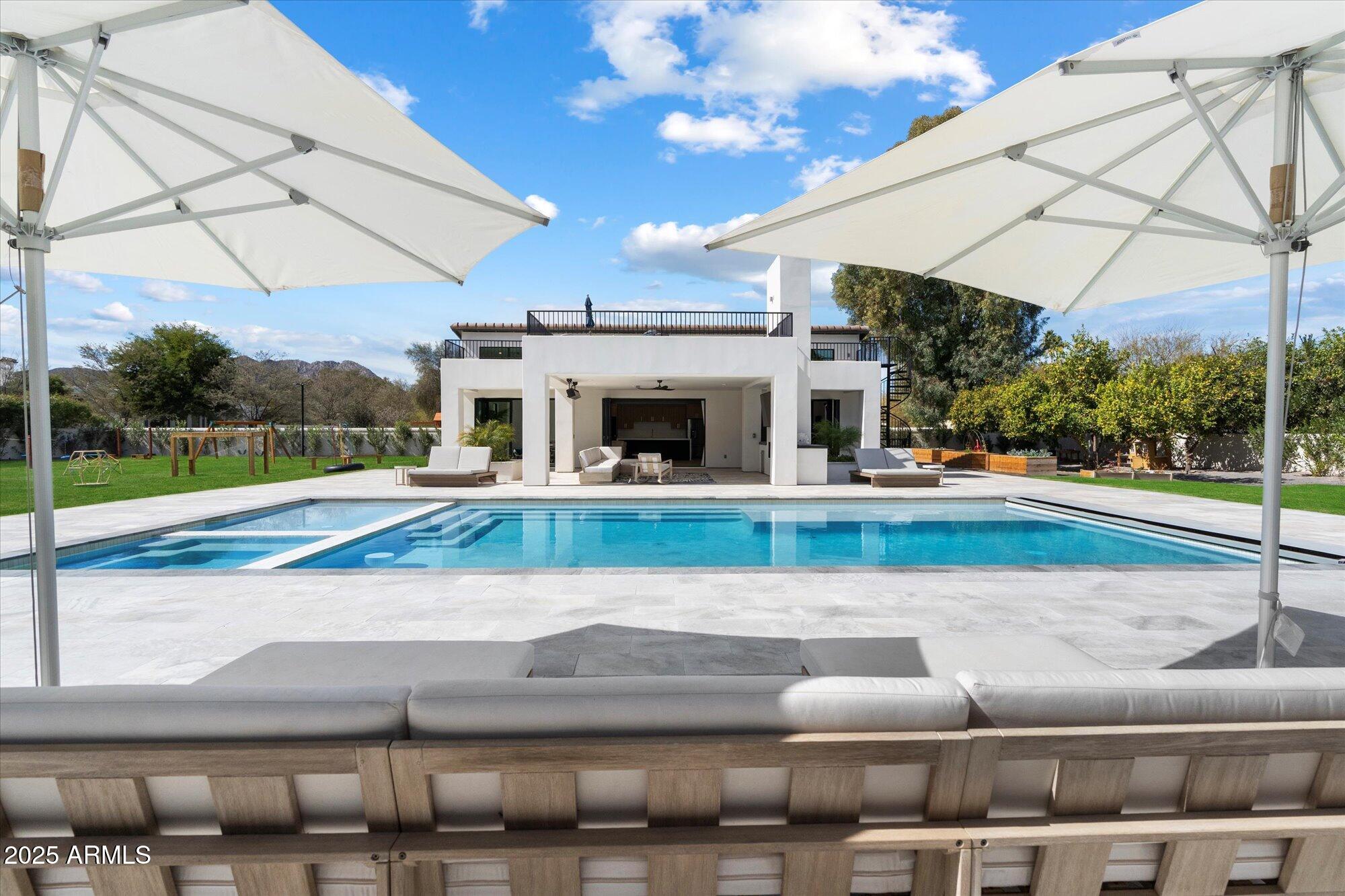 Located in Arizona's wealthiest zip code, 85253, this reimagined Santa Barbara-style estate sits in the lush, green Camelback Country Estates neighborhood. Designed for wellness and luxury, it spans over an acre of fully utilized grounds-no wasted space. Minutes from Cherokee Elementary, it includes a 4BD/5BA main home and a brand-new 2BD/1BA guest house around a fully redesigned backyard. Citrus trees, gardens, and lawns frame a saltwater pool with UV & CO2 systems, spa, sport court, putting green, and playground.  Inside, a chef's kitchen with dual islands opens to a vaulted family room; the primary suite includes a fireplace and spa-like bath with sauna and outdoor shower. A rare blend of elegance, wellness, and family living in Paradise Valley.