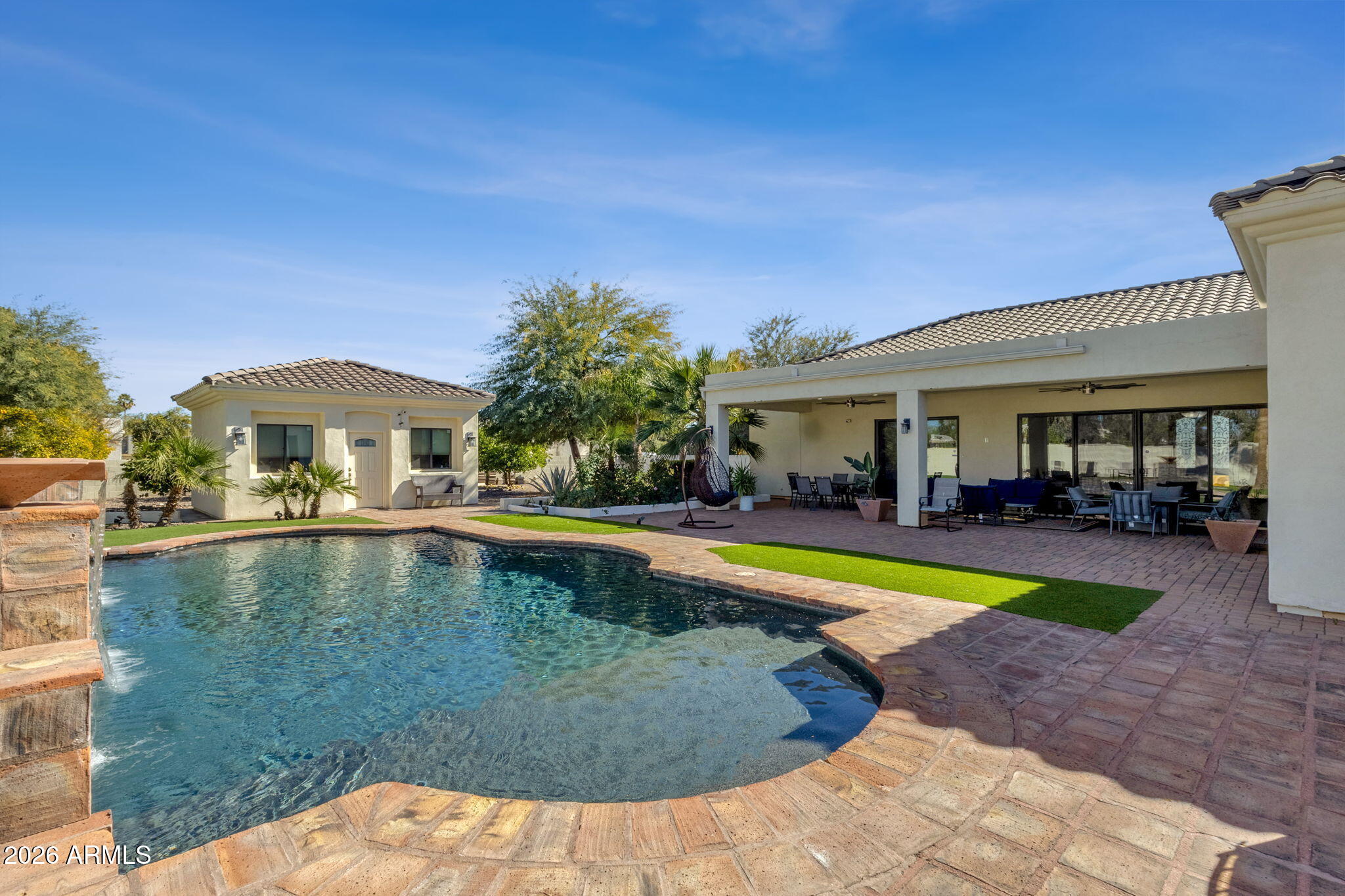 WOW!!! LOOK AT THAT PRICE!!!  Located in the highly sought-after Cactus Corridor, this exceptional multi-generational property offers rare flexibility with multiple independent living spaces and a detached guest house, thoughtfully designed for privacy, comfort, and entertaining. This floorplan was ahead of its time. The main residence features expansive open-concept living areas with soaring ceilings, architectural tray details, recessed lighting, and stone flooring throughout. A dramatic fireplace with custom built-in shelving anchors the primary living room, complemented by a custom built-in bar with counter seating, ideal for entertaining and casual gatherings. The home features a dedicated movie theater room designed for watching movies, streaming, and entertainment use. Multiple seating and dining zones flow effortlessly across the space, while large sliding doors open to covered patios and the backyard, creating strong indoor-outdoor connectivity for everyday living and hosting. The chef's kitchen serves as the centerpiece of the home, featuring custom dark wood cabinetry, granite countertops, and a large center island with seating ideal for casual dining and entertaining. High-end stainless-steel appliances, including built-in wall ovens and a full-size refrigerator, are paired with generous prep space, pendant lighting, and abundant storage. The kitchen opens directly to both living and dining areas, supporting effortless hosting and everyday functionality. This unique property includes a detached guest house complete with kitchen and bathroom well suited for extended household living or long-term guests. Outdoor living rivals a private resort, centered around a custom swimming pool with four cascading waterfalls that create both visual impact and ambient sound. The expansive backyard features multiple paver patios, covered entertaining areas with ceiling fans, and a built-in barbecue and outdoor kitchen, offering ample space for dining, lounging, and hosting. Mature landscaping and thoughtfully designed hardscape provide year-round usability and privacy.  Located across the street from the Jewish Community Center AND from one of Scottsdale's most coveted elementary schools, Sonoran Sky. Shopping, dining, and entertainment are very close by with Cactus Park & Aquatic & Fitness Center is approx. 2.0 miles, providing recreation facilities, walking paths, and green space close to home. Kierland Commons 1.6 miles and Scottsdale Quarter 1.6 miles. Scottsdale Airport is 2.8 miles, while TPC Scottsdale 2.8 miles and WestWorld of Scottsdale 5.8 miles. Convenient access to Loop 101 connects the home to North Scottsdale, Paradise Valley, and the greater Phoenix metro. A rare opportunity combining scale, versatility, and location in one of Scottsdale's most connected neighborhoods.