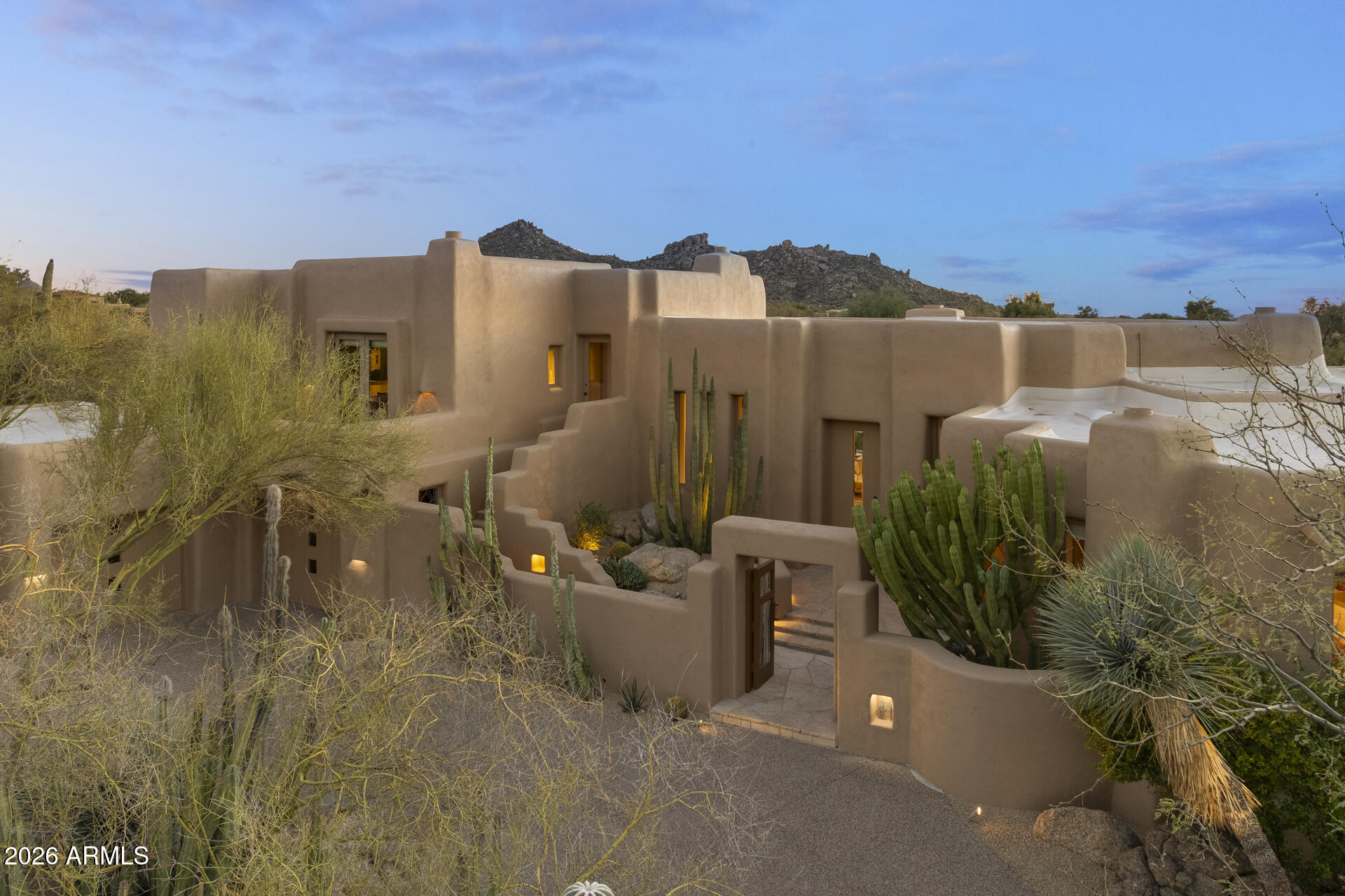 William (Bill) Tull, renowned artist & sculpter, designed this private adobe retreat which offers complete privacy within the famous ''Boulders Resort.'' This custom adobe home on the 17th green of the Boulders south course is 1 of only 17 architecturally unique houses in the Tull inspired ''Adobe De La Tierra'' subdivision. South facing patio provides fairway, mountain & gorgeous sunset views. 7 fireplaces, 6 bathrooms, 4 bedrooms, 5016 square foot home features hand-sculpted, custom shaped rooms. Circular drive takes you to two cactus spine gates leading to a private courtyard. Enter the home to a large great room w/dramatic views. Make your way through a mini family room - great for reading, movies, games, or a sitting room-on the way to the primary room with separate his/her (see more) bathrooms, mountain views and an outside sitting area. One bedroom has an exterior entrance perfect for a nanny, caregiver or a relative who has returned.
All bedrooms are separated and several have an ensuite. Kitchen opens to the patio w/BBQ for outdoor dining. Kitchen has all of the bells and whistles including  two dishwashers, beverage refrigeration drawers and many top of the line appliances. Breakfast nook is cozy with art niches.
The great room and kitchen/family room feature many niches and  abundant wall space for art. Saguaro ribbed window coverings and air vents all make for a distinct Santa Fe feel. This home is authentic adobe, meaning it was constructed with handmade solid bricks from the earth. The result is a home built with exceptional quality and care, boasting unparalleled efficiency for the desert climate. Room for a guest house and/or a pool on the private ¾ ace lot.  The south facing wrap around patio has several viewing areas and sports a water feature and a romantic firepit.
The home was remodeled/expanded twice, the first with true adobe and the second using standard block.
The Boulders Resort features 2 golf courses and three types of membership. Bill Tull adobes rarely come on the market.