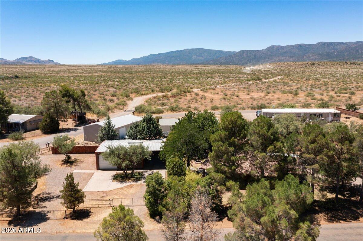 Situated on a spacious .55-acre corner lot, this lovingly maintained 1988 manufactured home offers approximately 1,000 sqft of comfortable living space with 2 bedrooms and 2 full bathrooms. The open-concept living, dining, and kitchen area creates a welcoming atmosphere, while a cozy wood-burning stove provides extra warmth during the winter months. Additional features include a newer A/C unit, electric furnace, pantry and an additional freezer, plus a versatile office/flex room and dedicated laundry area. Enjoy Arizona living from the expansive covered front and side porches, complete with a heated spa tucked in for privacy . Outside you'll find a 10' x 16' workshop, chicken pen, fenced backyard with raised garden and flower beds, fire pit gathering area, and........PLEASE SEE MORE....... CONTINUED......and plenty of room to enjoy the outdoors. The fully fenced property features three double rolling gates, a circular driveway, RV parking with electrical hookup and water, and an abundance of mature pine trees providing shade and privacy. A standout feature is the impressive 30'x44'  partially insulated steel workshop!! It includes a 10'x12' roll-up door, pellet stove, 220-volt outlets, ridge vent, abundant electrical outlets, LED lighting, an air hose reel with exterior compressor wiring, and an exterior 220-volt outlet for an air compressor (air compressor not included). For even more possibilities, the adjacent .28-acre vacant lot is also available for purchase for $59,000, offering the opportunity to own a combined .83 acres, mls #7049926
