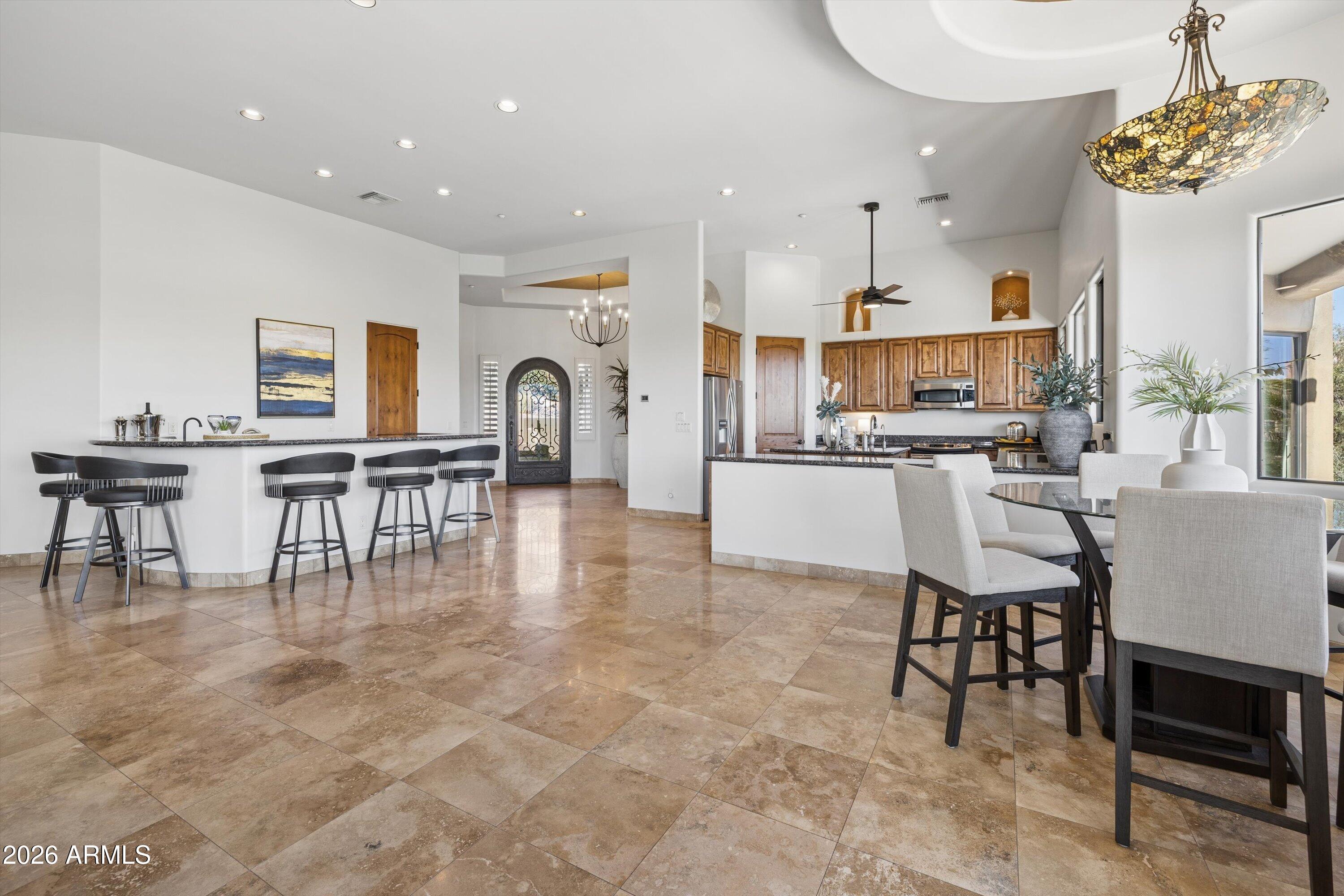 Embrace the beauty of desert surroundings in this exceptional 4-bedroom, 3.5-bath residence offering expansive living spaces, abundant natural light, and 4 Peaks views. High ceilings and an open-concept design create an airy sense of volume and comfort, while the great room is anchored by a striking Cantera stone fireplace, granite wet bar, and wine closet--perfect for relaxed luxury and entertaining. The well-appointed kitchen features stainless steel appliances, center island, pantry, and a generous dining space. A nearby flex area is ideal for media or formal dining, while the den w/closet offers flexibility as a guest suite or additional bedroom. Outdoors, a resort-style setting with heated pool, seamless desert beauty, and layered mountain views create a truly serene retreat.