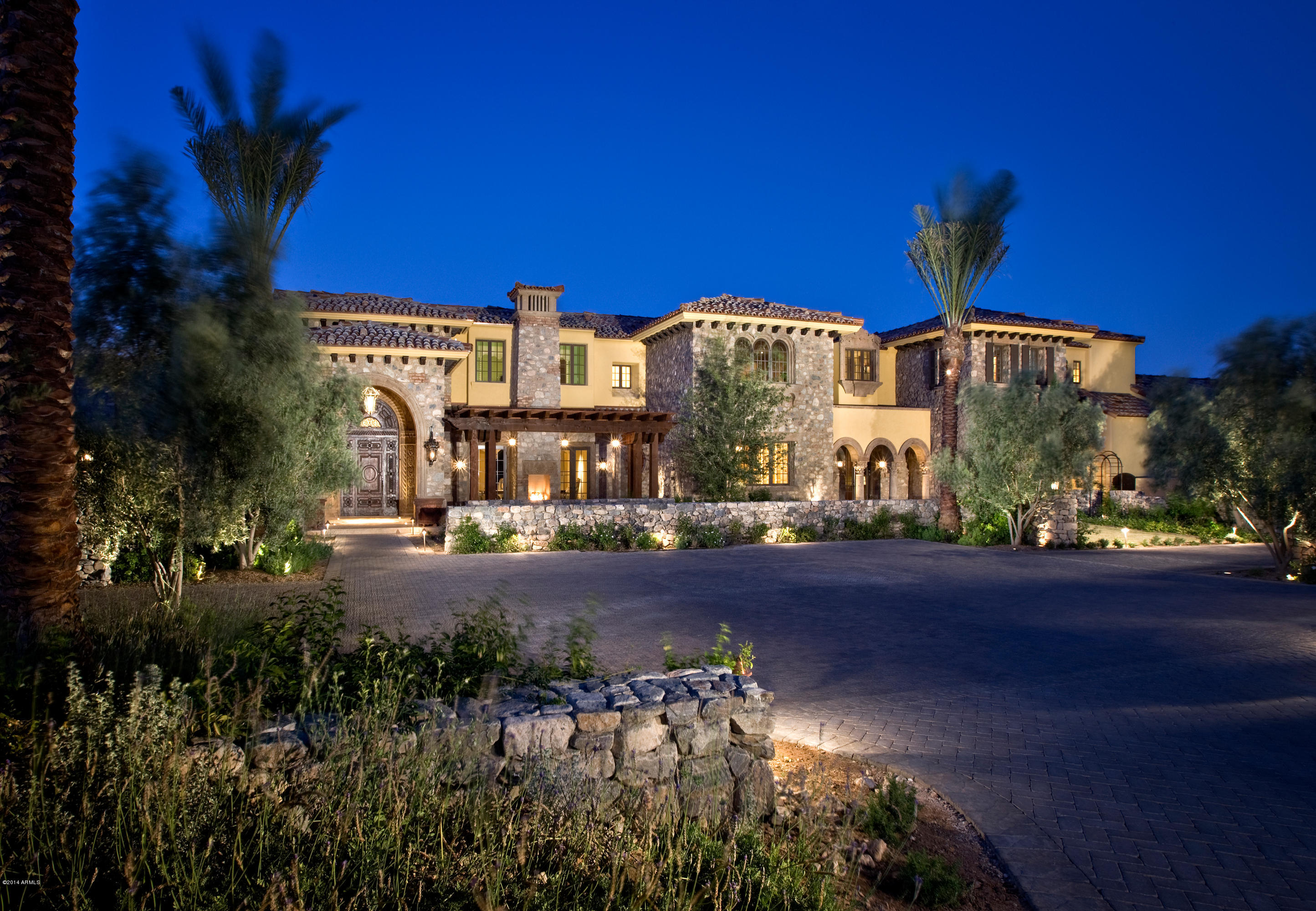 Lush palm trees, flowering plants and a stone archway lead to the intricate wooden door and paradise beyond. Designed by Erik Peterson, this 5-acre Mediterranean estate features timeless details such as wrought iron accents, wooden shutters, and handcrafted cabinetry, while offering the very best in home entertainment. Revel in the exquisite craftsmanship, fine finishes and custom features inside, including your own home theater and recording studio. Host a grand gala under the stars around your resort-style pool area, cabana and fire pit. After a friendly tennis match, retreat to your spa-like master sanctuary for a rejuvenating bath, then watch the desert sky from your private terrace. Perfectly situated at the base of Mummy Mountain; here, sweeping views surround you.