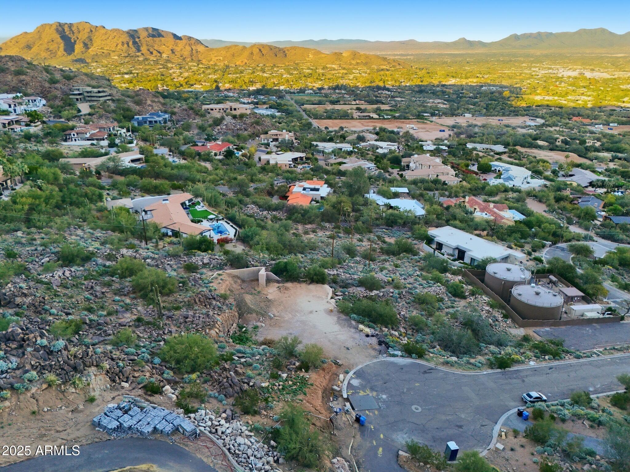 A rare opportunity awaits on the north side of Camelback Mountain. This hillside lot spans over an acre and comes with plans ready for permits, offering the perfect canvas for a custom two-story modern estate with amazing views. Located within a gated community of Cholla Heights, which is comprised of only seven homes, each showcasing contemporary architecture, this is the final gated community available on the iconic Camelback Mountain. Just minutes from Scottsdale's premier dining and shopping, the setting is truly unmatched.
As part of this private enclave, the property boasts sweeping mountain and city views. The contemporary design envisions 6,734 sq. ft. of living space with a level entry and soaring 25-foot glass windows that bring the outdoors in. The full set of complete drawings presently features a gym, home office, movie theater, and four-car garage. Outdoors, facing the mountain views to the east is nearly 1,000 sq. ft. of entertainment space, including an infinity pool and spa, perfect for enjoying the incredible views.
A unique feature for a mountain lot is a rare private backyard. This property offers an additional 1,000 sq. ft. of private yard set against a rising mountain slope, providing complete privacy as you relax in the heated spa. 
An unparalleled opportunity to create a truly one-of-a-kind home in one of Paradise Valley's most desirable locations.