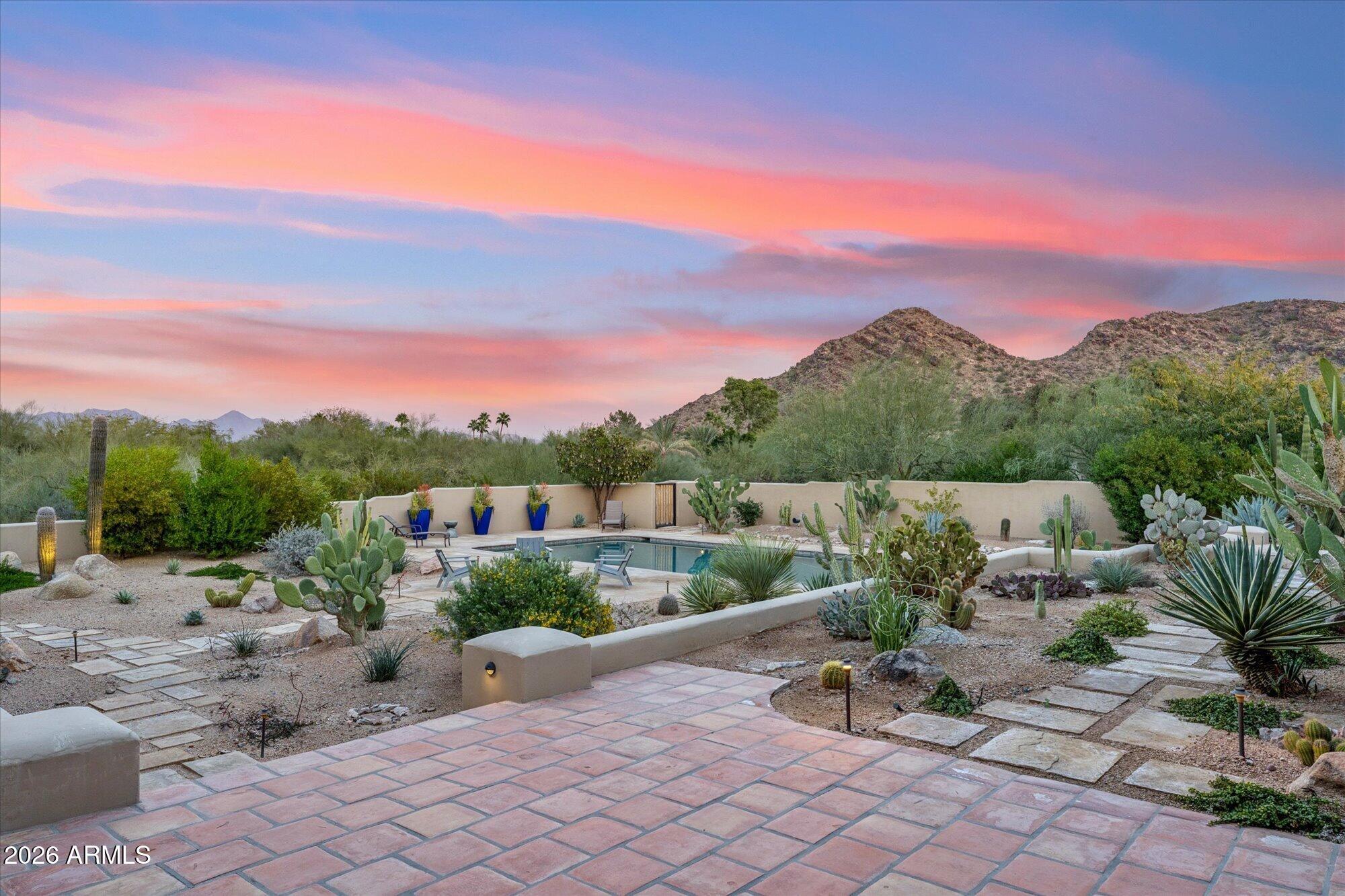 Set on nearly three pristine acres in the heart of Paradise Valley, 5060 E Desert Sky Lane is a true Hacienda estate where panoramic mountain views, timeless Territorial/Santa Fe architecture, and extraordinary future potential converge.

Perfectly positioned on a private corner lot ,the home captures sweeping 360° views of Paradise Valley's most iconic mountain ranges -- Camelback Mountain, Mummy Mountain, the Phoenix Mountain Preserve, and distant McDowell Mountain vistas -- visible from nearly every window and outdoor living space.

Authentic old-world craftsmanship defines the residence. Dramatic wood beams span both indoor and outdoor ceilings. Hand-carved solid wood doors, rounded plaster walls, hand-forged lighting, 12 ft plus ceilings in living room, skylights, and four fireplaces create a warmth and architectural integrity rarely found today. Clerestory windows and abundant natural light enhance the connection between the home and the surrounding desert landscape.
The estate is uniquely composed of a substantial main residence of over 5,000 square feet with an attached casita with kitchenette.  In addition, there is a 2,400+ square foot guest house (built 2012) complete with its own garage, yard, kitchen, office, great room, laundry, and high ceilings throughout, the guest house comfortably housed the owners for over a year during renovations offering exceptional flexibility for guests, multi-generational living, or a private retreat.
Inside the main home, thoughtful updates blend seamlessly with the property's architectural character. The renovated kitchen features new appliances, dual dishwashers, granite counters, mesquite cabinetry, an oversized island, and a butler's pantry, opening to expansive covered patios designed for effortless indoor-outdoor living. Additional spaces include a dedicated library, gym, private guest wing with its own living area and patio, and multiple en-suite bedrooms positioned to capture mountain views.
The primary suite is a retreat of its own, showcasing views of Mummy Mountain and the McDowells & private access to the pool and spa.
Outdoors, the property unfolds into a private desert compound designed for both entertaining and recreation. Amenities include a heated oversized pool, pickleball/sports court, fire pit with banco seating, desert greenery, circular paver drive, gated courtyard entry with fountain, and parking for 20+ guests. The estate offers ample room to add additional garages or structures for the car enthusiast.
With acreage that is increasingly rare in Paradise Valley, authentic Territorial architecture that cannot be replicated, and uninterrupted mountain views in every direction, 5060 E Desert Sky Lane represents not only a beautiful residence , but a remarkable canvas for expansion, reimagination, or the creation of a legacy estate unlike anything else in the Valley.