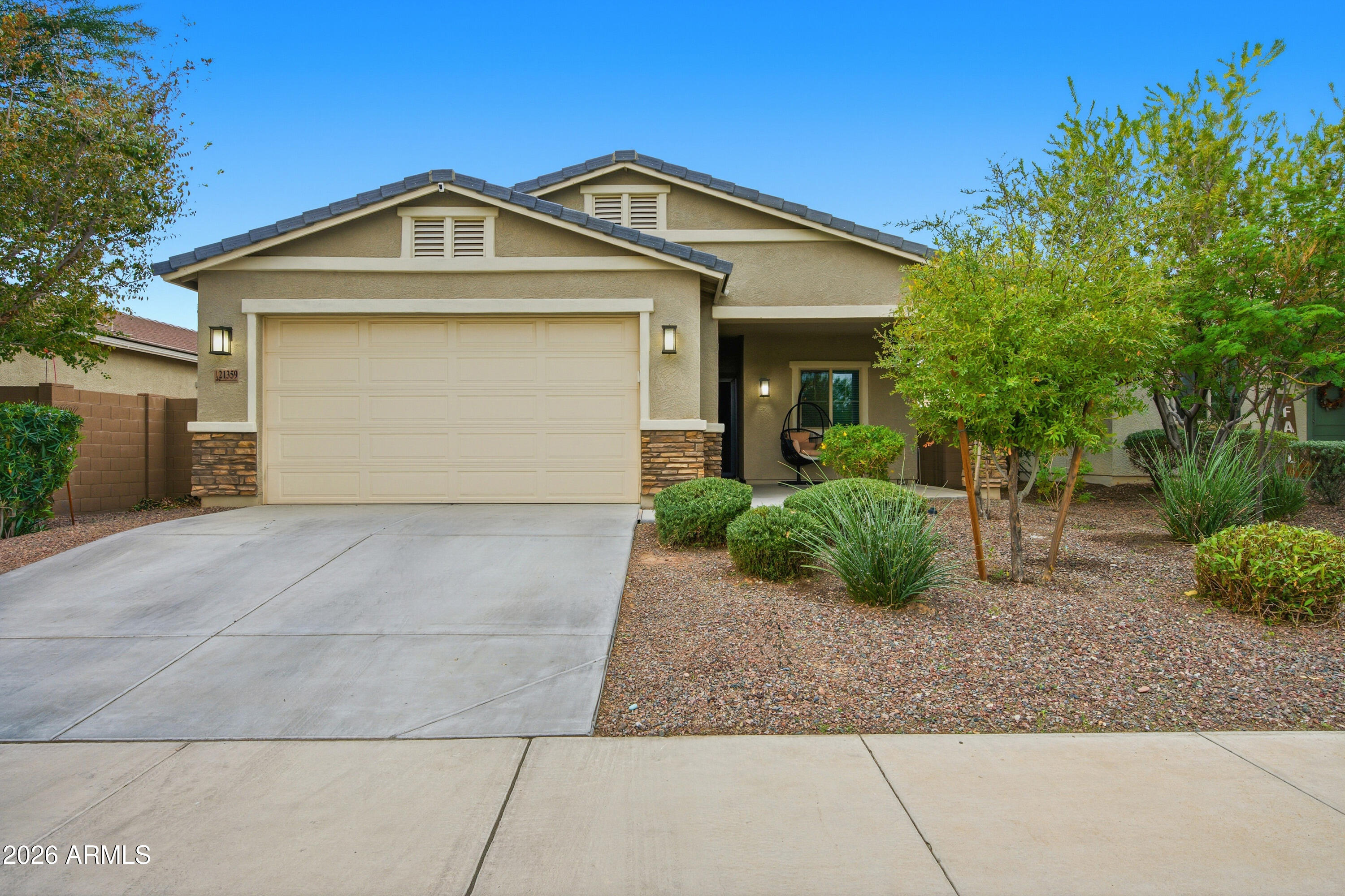 Freshly painted and move in ready! This 4-bedroom, 2-bath home offers beautiful White Tank Mountain views and a functional open concept floor plan perfect for everyday living. The kitchen features granite countertops, stainless steel appliances, and a gas range, opening to the main living spaces for easy entertaining and family connection. Enjoy wood look tile, ceiling fans, and blinds throughout. The spacious primary suite includes a walk in closet and private ensuite. Step outside to a low maintenance backyard with artificial turf and a covered patio. The front porch overlooks one of the largest parks in the community with basketball courts, soccer fields, and a playground, all just minutes from the neighborhood school and community amenities.