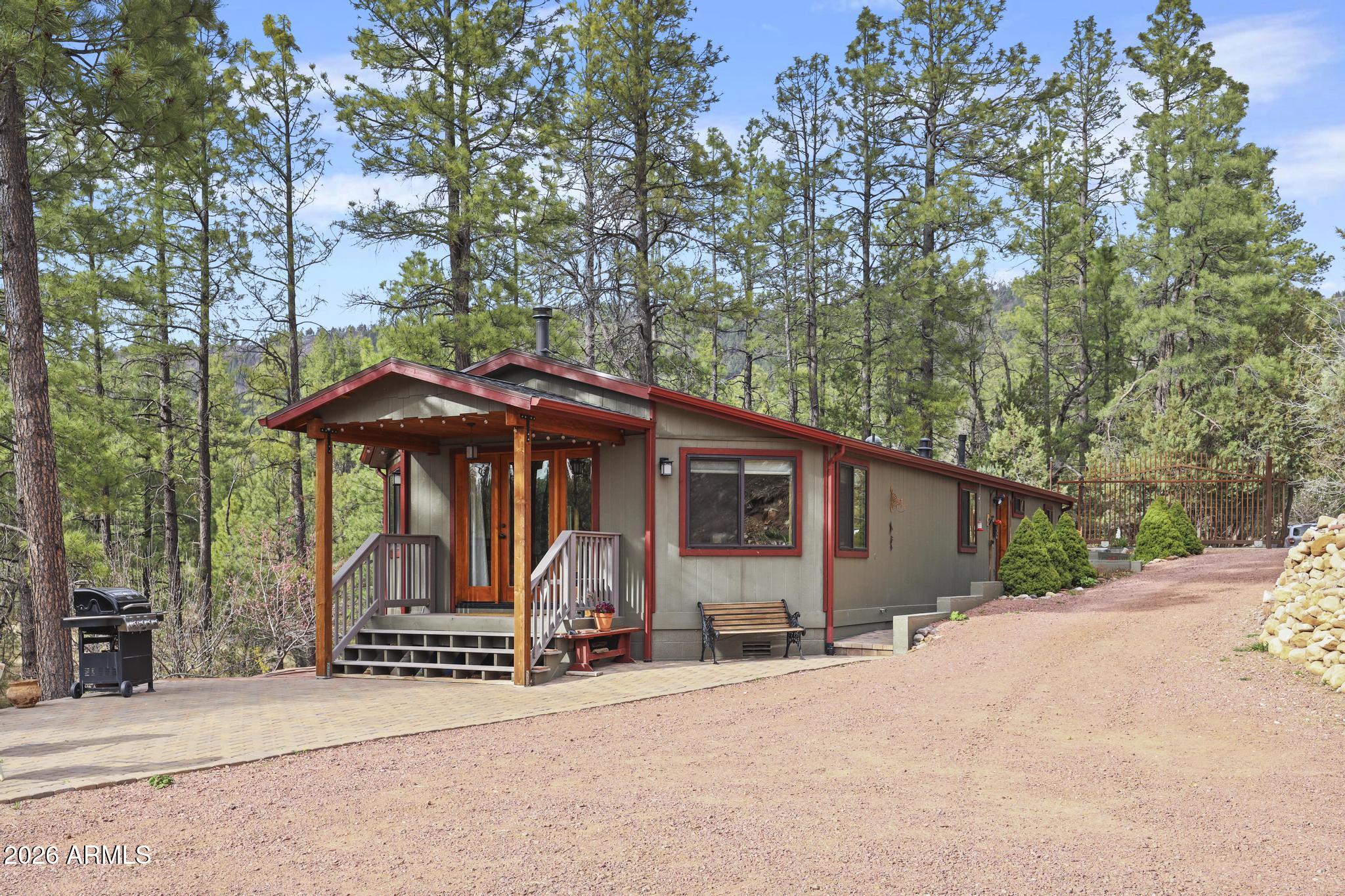Rare opportunity to own a 1.48 acre private mountain compound in Ponderosa Springs, just below the breathtaking Mogollon Rim. Located at the end of a quiet cul de sac, this gated and fully fenced property offers exceptional privacy and a private well.  The remodeled main home offers 1,457 square feet, including a 318 square foot site built living room addition completed in 2017. Also on the property is an oversized two car garage with a workshop and an 840 square foot guest house above, complete with its own full bathroom.  The main home features two bedrooms and two bathrooms and has been extensively remodeled with upgraded electrical, new drywall, updated bathrooms, a new tub and shower, and quality cabinetry throughout. The updated kitchen includes quartz countertops, new appliances, custom cabinets, a built in desk area with glass china cabinets, and a beautiful live edge juniper slab countertop.  Engineered hickory wood flooring and tongue and groove pine ceilings add warmth and mountain charm. The detached oversized garage with guest house above was built in 2015. The 30 by 28 garage provides exceptional storage, a workbench, two closets, a private workshop, and a washer and dryer.  The 840 square foot guest house offers an open living area, full bathroom, wood stove, gas wall heater, a 50 gallon hot water heater, engineered hickory flooring, and tongue and groove pine ceilings, ideal for extended family, guests, or multigenerational living.  The entire property is fully fenced and features multiple fruit trees, willow, aspen, Italian cypress, Arizona cypress, and a variety of flowering plants and bulbs throughout. Additional highlights include three outbuildings, a well house, plenty of room for recreational vehicles and equipment, and a large fenced in garden.  There is even an amazing treehouse with its own deck for the kids. The property is fully gated and fenced to help keep elk and deer out while preserving your landscaping and garden space.  Ideal for a private retreat or hunting getaway, this property is located in the cool mountain air at the base of the Mogollon Rim and offers easy access to national forest land, outdoor recreation, and abundant wildlife.  Whether you are searching for a secluded Arizona mountain home, a hunter's retreat, a multi family compound, or a private oasis with guest quarters and workshop space, this property delivers flexibility and value. Meticulously maintained, with pride of ownership throughout. Furnishings and all appliances are included.