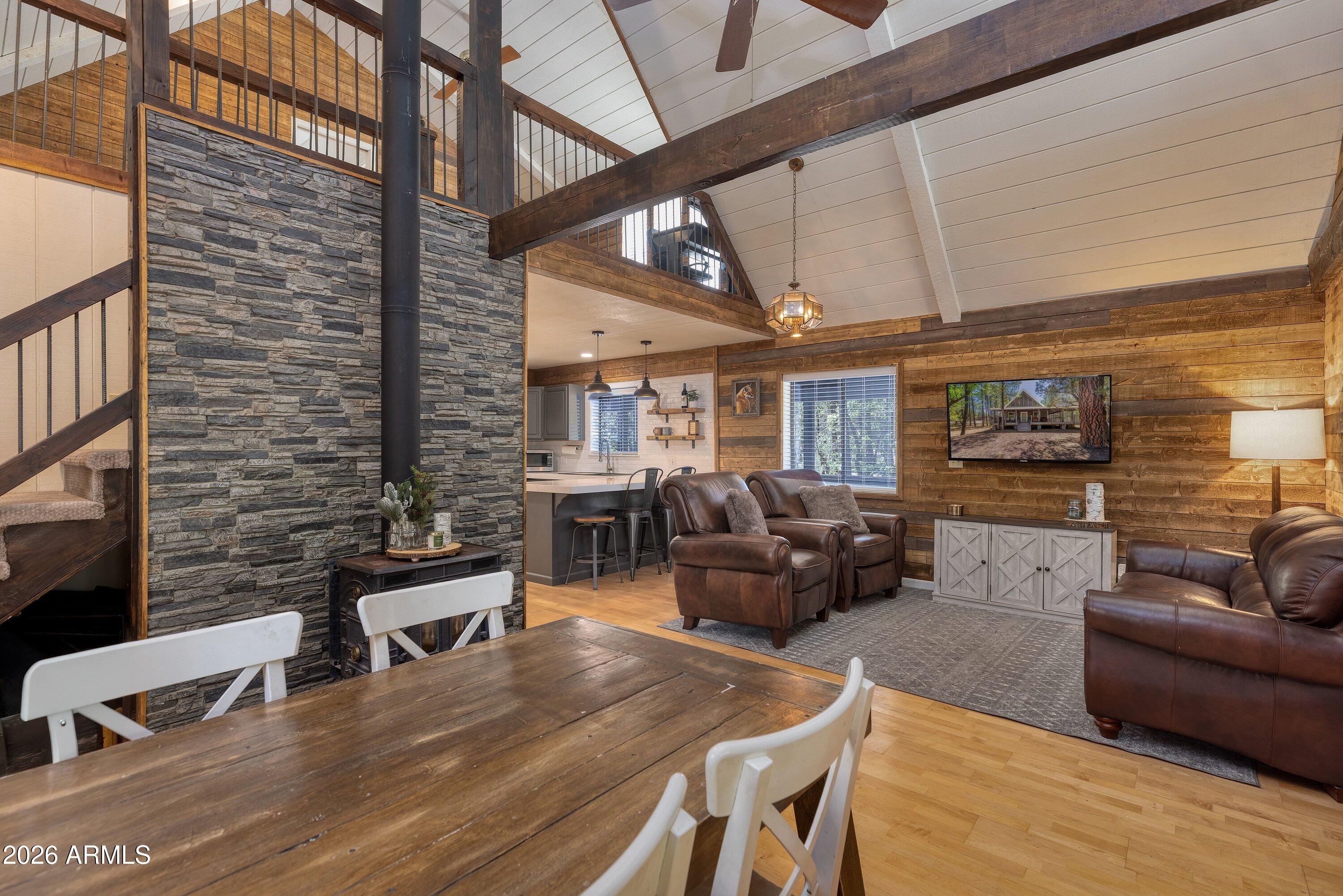 Imagine escaping from the pace of city life, following a quiet driveway into the trees, and arriving at your own private mountain sanctuary on a sprawling 0.82-acre lot in the heart of Lakeside. This completely remodeled cabin at 1351 Ox Bow Dr is a perfect fusion of rustic knotty pine charm and refined modern luxury. Offered fully furnished, it delivers instant mountain living--turn the key and step directly into comfort, ease, and escape.

Inside, you're welcomed by an effortlessly inviting aesthetic anchored by a stunning gourmet kitchen that blends contemporary elegance with warm cabin character. Enjoy gleaming white quartz countertops, rich wood accent walls, a classic white subway tile backsplash, a deep farmhouse sink, and a spacious walk-in pantry. The generous breakfast bar, illuminated by industrial pendant lighting, sets the stage for effortless entertaining--perfect for guests to gather with a glass of wine while you prepare a post-adventure meal.

The kitchen flows seamlessly into a breathtaking great room, where soaring vaulted ceilings and a dramatic wall of high-set windows frame the surrounding ponderosa pines like living art. Warm knotty pine detailing wraps the space in timeless mountain charm, while a premium woodstove invites cozy evenings spent fireside. Above, a versatile loft adds valuable bonus space--ideal as a game room, kid's retreat, or additional sleeping quarters for guests--complementing three comfortable bedrooms and two bathrooms.

Outdoor living is equally exceptional. A massive, low-maintenance wrap-around covered deck extends your living space into the trees, creating the perfect setting to enjoy Arizona's beautiful four-season climate. Set on nearly an acre, the property feels wonderfully private and peaceful, complete with a whimsical custom-built backyard treehouse that adds a touch of magic. A sleek, durable metal roof enhances both style and long-term peace of mind.
Although it feels like a secluded retreat, this home is ideally located in the heart of town--just minutes from kayaking and fishing at Rainbow Lake, hiking and exploring around Woodland Lake, and close to local bistros, breweries, and everyday conveniences. Whether you're seeking a turnkey second home, a high-performing short-term rental, or a full-time mountain escape, this property delivers it all. Just bring your suitcase--your life in the pines is ready to begin.
