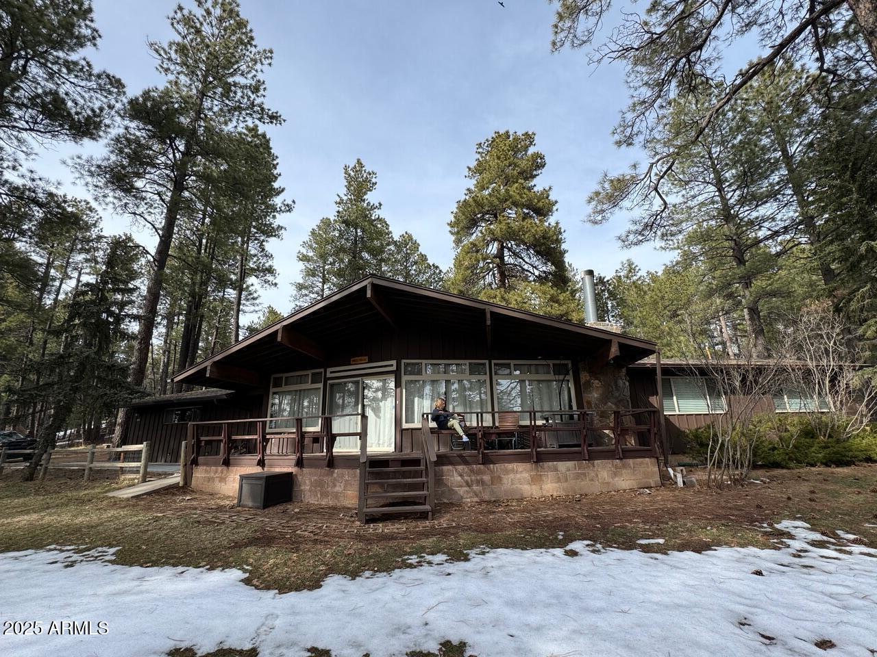 Welcome to Munds Park. This 3-bed, 2-bath cabin sits on just over an acre of mature Ponderosa pines in the heart of the community. Rich in local history, the property once housed the original local country club, and its iconic rooflines and architectural character are still reflected in the clubhouse today.
The home has been fully remodeled with updated electrical, plumbing, and insulation. It currently boasts a 5-star rating as a short-term rental with strong demand. Inside, you'll find an updated interior with a stone fireplace, open kitchen, and modern finishes. All three bedrooms offer natural light and views of the surrounding pines. The front porch provides a front-row seat to local parades on Pinewood Blvd, making it one of the best locations in Munds Park for the holidays. The property offers additional flexibility, with the option to purchase fully furnished, creating a turnkey rental or second-home opportunity. The community also provides access to the Pinewood Country Club (membership required), golf course, community spa, and nearby lake.
Don't miss this rare acre-plus opportunity in the heart of Munds Parkclose to recreation, community events, and everything the area has to offer!