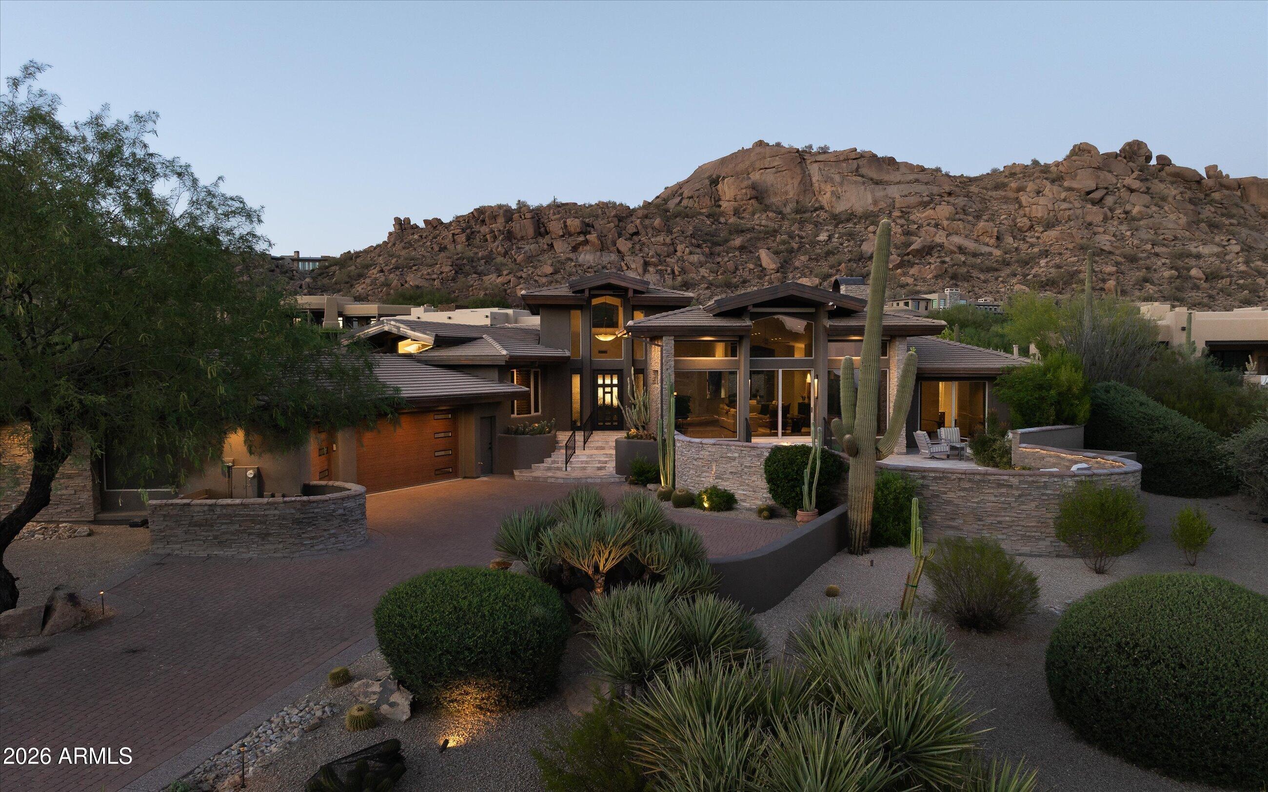 Welcome to Terra Sol, a recently renovated custom home with panoramic sunset and Pinnacle Peak views in guard-gated Estancia. Open, great room floor plan includes 3 bedrooms plus an office, exercise room and oversized utility room.  Chef's kitchen with new SubZero, Thermador and KitchenAid appliances plus an new, chilled wine room with storage for 350+ bottles. Completely renovated backyard with stone paver decking, heated pool/spa, covered ramada area with built-in heaters,  a large linear, gas fire pit plus an outdoor kitchen with BBQ, refrigerator and sink. Exterior architectural details include an extensive blend of stacked stone and glass with copper roof facia detail.  Recently update interior finishes include tile and wood flooring, custom cabinetry, granite slab counters and stacked stone and glass with copper roof facia detail.  Recently update interior finishes include tile and wood flooring, custom cabinetry, granite slab counters and stacked stone wall details. An oversized 3-car garage completes the residence.