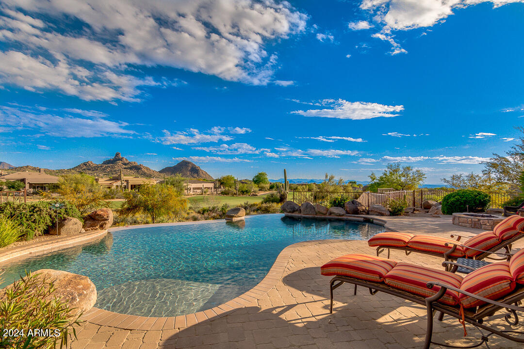 Arizona living at its best in this 5,391 sq ft custom home within Talus, a gated golf community in Troon North. Set on 1.092 acres, revel in unmatched panoramic mountain, golf course, and city light views—NO obstructions, just breathtaking scenery. Enjoy stunning sunsets over the 3rd fairway of the renowned Monument Course. Inside, meticulous craftsmanship and attention to detail shine. The chef's dream kitchen boasts Sub-Zero & Wolf appliances, a walk-in pantry, and a pass-through window to the outdoor BBQ kitchen. The great room features a gas Cantera fireplace and floor-to-ceiling glass framing Pinnacle Peak & Thompson Range. The primary retreat offers a private patio, spa-like bathroom, and a flex room/gym. Main-level highlights include a private office, dining room, ensuite bedroom w/ separate entrance, and a laundry room. 

Upstairs, a 1,315 sq ft private wing welcomes guests or family with two bedrooms, two full baths, a wet bar, and a family room with a view deck.

Step outside to your resort-style oasis with a heated pool & spa, misters, gas fire pit, outdoor kitchen, and multiple entertaining areas. The 4-car garage with built-in storage completes this beautiful home.