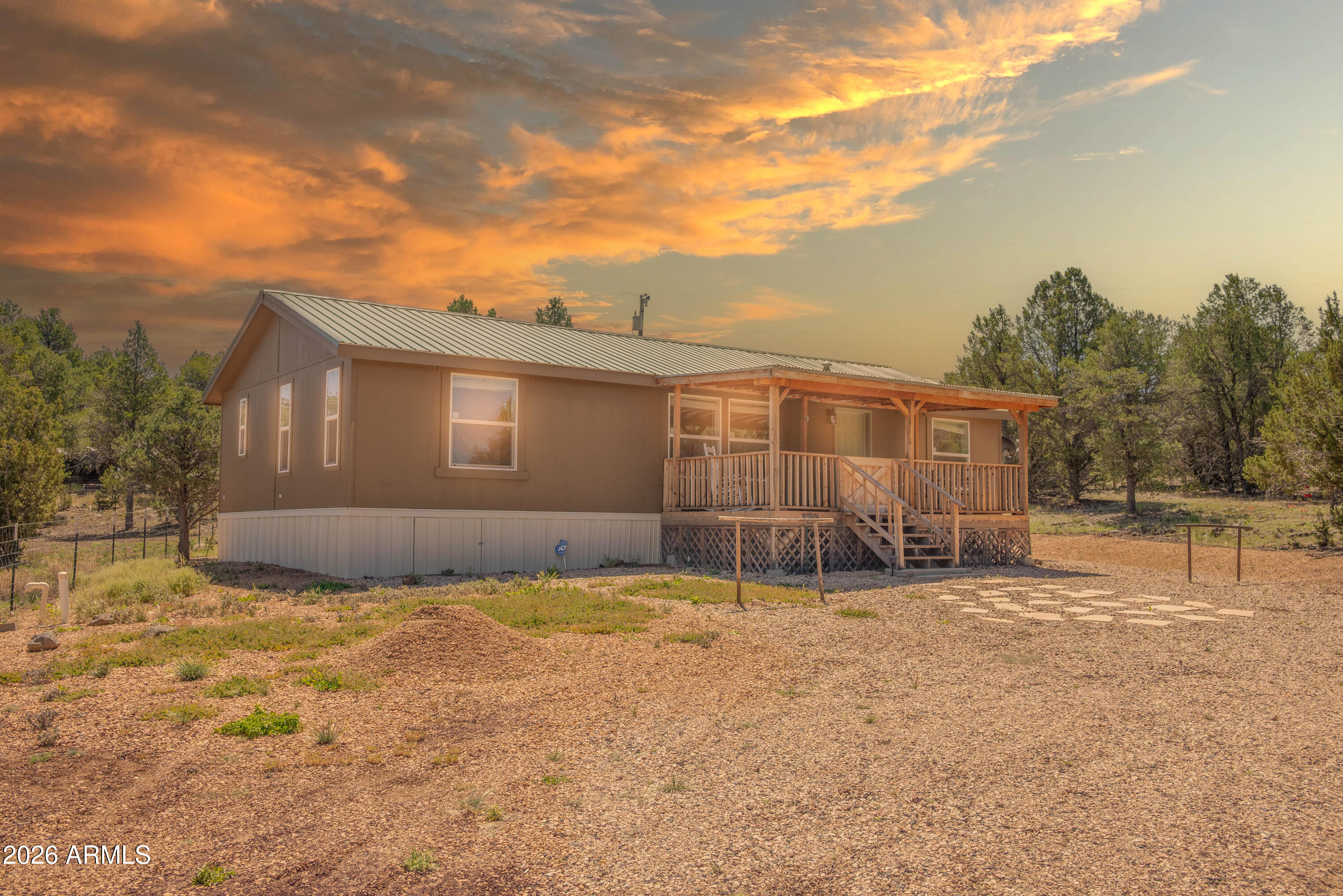 Fully Furnished Home or Vacation Rental This move-in ready  property combines a like-new 2018 manufactured home with a spacious one-acre lot, offering modern living and expansive outdoor freedom with no HOA restrictions. Turnkey 3-Bed, 2-Bath on 1 Acre. Embrace the perfect balance of a Modern Western Themed Cabin and rural freedom. This property features a beautifully maintained  open-concept floor plan. With a large front porch for entertaining and watching the sunsets over the mountains. A Newer Air Conditioning plus a Metal Roof for low maintenance. The Cinder Circular Driveway has room for all your 4 wheelers.  Also Decorative Landscaping in front yard, featuring mature trees.