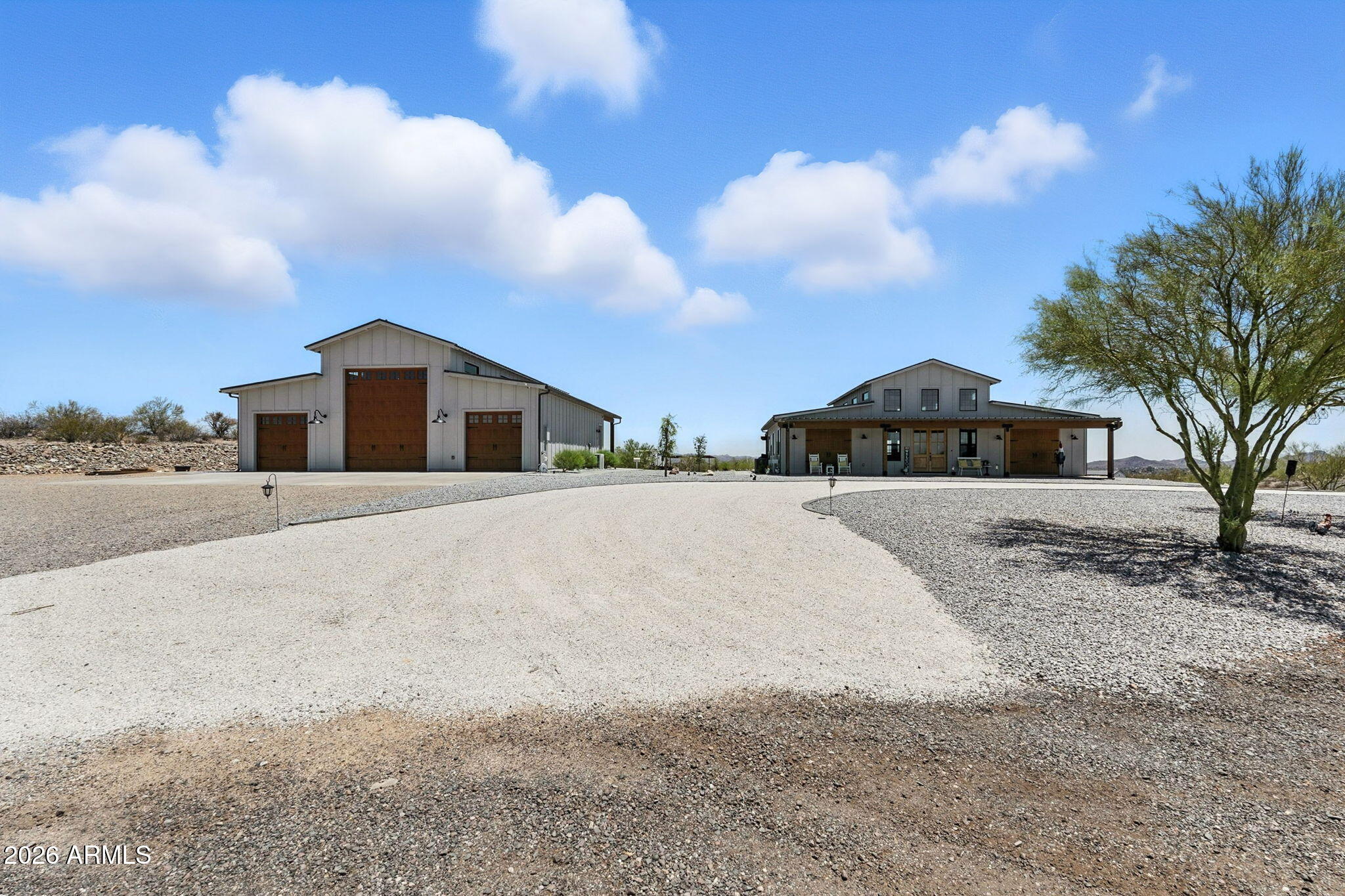 Gorgeous Custom Home, with the best views in Wickenburg on over 6 acres! Refined modern Barndominium farmhouse architecture at its finest! Charming ranch-inspired design throughout with over 2800 sqft of living space! The main home offers 3 bedrooms and 2 bathrooms, totaling 2080 sqft. This property also includes a 737 SqFt Guest House with an additional 1 bed/1 bath--and a detached 1387 SqFt RV garage. Showcasing an expansive full-length covered front porch...and a full-length covered back patio.  Dual wooden faux carriage-style doors flank a central glass-paneled entry, creating strong curb appeal and balanced design.  Clean gravel landscaping and a straight paver walkway enhance the crisp, ranch-inspired aesthetic. Inside, the home offers an open-concept great room with soaring vaulted ceilings and exposed wood beams...Clerestory windows flood the space with natural light, while wide-plank wood-look flooring adds warmth. The kitchen is anchored by a large island with farmhouse sink, stainless steel appliances, white shaker cabinetry, quartz countertops, and a brick backsplash. Statement ceiling fans and modern-rustic lighting reinforce the farmhouse character.

The rear covered patio spans the width of the home, featuring wood beam detailing, pre-wired for ceiling fans, and ample space for lounging and dining. A glass overhead-style door creates seamless indoor-outdoor flow, ideal for entertaining while enjoying expansive desert views. The property blends rural tranquility with polished, high-end finishes. Bring your toys and don't miss the chance to make this beauty yours!  RV garage has a 50A receptacle for the RV. as well as an additional 50A  in the standard garage bay for EV charging. Shared Well and Septic connected.