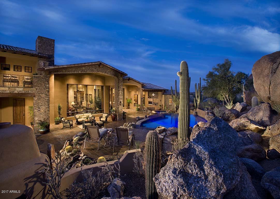 Builder's personal residence! Great opportunity to own 3 1/2 acres of Troon Mountain with sweeping down-valley city light & sunset views while tucked in the boulder outcroppings at the base of Troon Mountain. This rare setting offers a resort-style backyard with a reverse negative edge pool meandering from the mountains with 3 water features & large spa. Several sitting areas, outdoor kitchen, fireplace, firepit, TV area & built-in cabinetry w/sink. Front courtyard offers water fountain, gated entry, firepit & sitting area capturing the city skyline!! A formal living room w/wet bar, cantera stone fireplace, wood beams in ceiling & custom niches. Formal dining room offers built-in buffet & cabinets, stone wall, dome ceiling w/custom chandelier & lighting, custom draperies & shades. Foyer offers brickdome ceiling w/custom lighting, wall sconces, large wood & beveled glass front door and custom slate design flooring medallion inlay. Great room features wagon wheel spoke wood beams, large stone fireplace w/wood mantel, floor to ceiling windows. Wolf and SubZero kitchen appliances, double refrigerators & freezers, 3 ovens, warming drawer, two dishwashers, 6-burner w/griddle Wolf range, large double islands, wine refrigerator, knotty alder cabinetry, wood ceilings, custom backsplashes, copper range hood, breakfast nook & large walk-in pantry. Wine Cellar, large laundry room, secondary stack washer/dryer in master closet, custom draperies, slate flooring, engineered Hickory wood flooring, knotty alder cabinetry & more. Upstairs game room, media room, office/den & secondary bedroom. Multiple upper-level balcony patios capture down-valley views as well as expansive mountain views w/boulder outcroppings. Large 2500sf 5+car garage offers hydraulic lift for additional bay (making this a potential 6-car garage), epoxy flooring, built-in cabinetry, air-conditioned garage, large workbenches w/sink! Home automation includes Crestron system, Lutron lighting system & security system! A fourth bedroom can be added to the upstairs. This is an immaculately maintained home offering pride of ownership & attention to detail!!