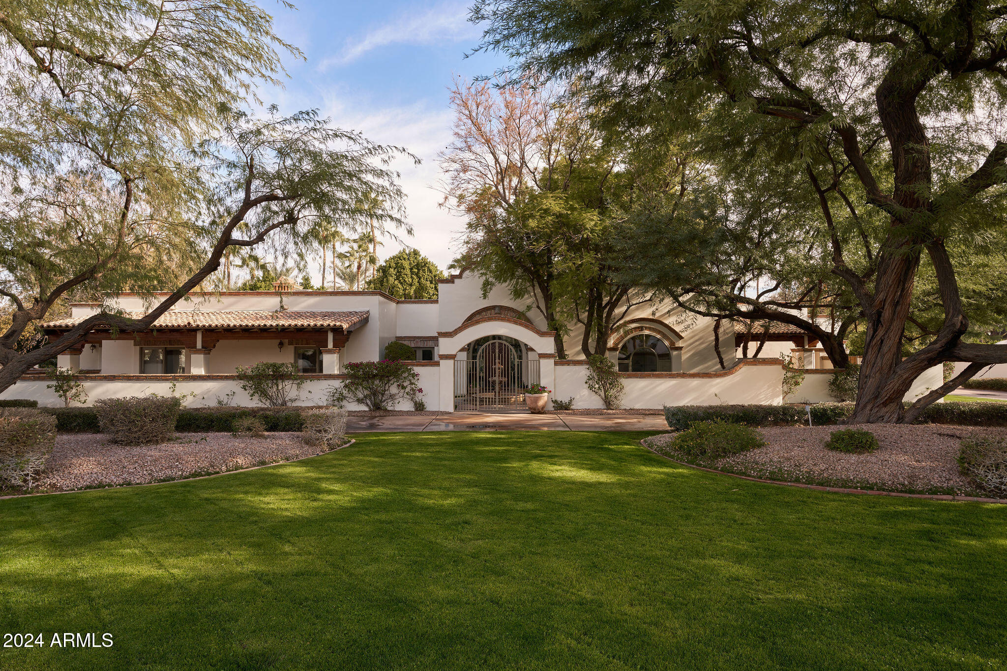 Welcome to 8145 N 68th Street in The exclusive Camelback Country Club.  This timeless Santa Barbara style home has a subtle Spanish influence with hand painted tiles in secondary bathrooms and stunning brick floors.  Smooth plaster walls and gorgeous wood flooring complement the simplicity of decoration.  High ceilings, arched windows, beautiful built-ins, wood burning fireplaces, French doors to the outside, and lovely ironwork add to the authentic feel of this fine home.  With a gorgeous updated kitchen and primary suite, you will feel like you are staying in a beautiful European retreat. 4 additional bedrooms provide plenty of space for family and friends.  There is a wonderful office, separate study, elegant living room, and a family room open to the kitchen. Patios and courtyards abound and elevate your sense of calm with the sound of trickling water from  carved, canterra fountains. The guest casita would be lovely for long term guests, or as a fabulous playroom/man cave.  The fully tiled pool is heated for year round enjoyment.  The grounds are something to behold with lush grass, mature trees and gorgeous flower beds.   A large covered patio with a built in BBQ is conveniently located right off of the kitchen.  With a 4-car garage and circular driveway, this home checks all of the boxes.