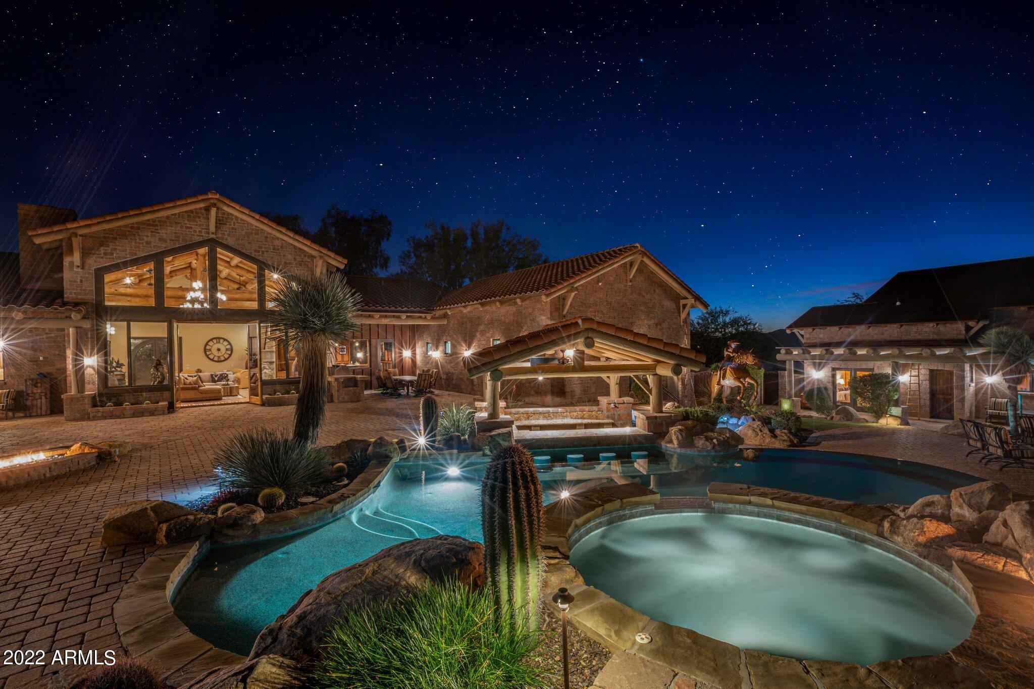 On the edge of 3 mil acres of parkland, the views from this gated estate are unmatched. The main house and guest house have 5 beds and baths, a grand living room, western saloon and private theater. The kitchen is equipped with a 72'' Sub-Zero refrigerator, 6 burner Wolf range with double ovens, beverage fridge and pizza oven. Car lovers will appreciate the 3 over-height garages with custom cabinetry. The resort backyard includes a negative edge pool with a swim up ramada, elevated waterfall spa and built-in BBQ. Enjoy mountain views from seating areas surrounding fire features. Outdoor adventure awaits with direct access to over 900 mi of hiking and horse trails. Included in the 3.2 acre, no HOA, property is an acre of flat land suitable for additional recreation space or a private stable