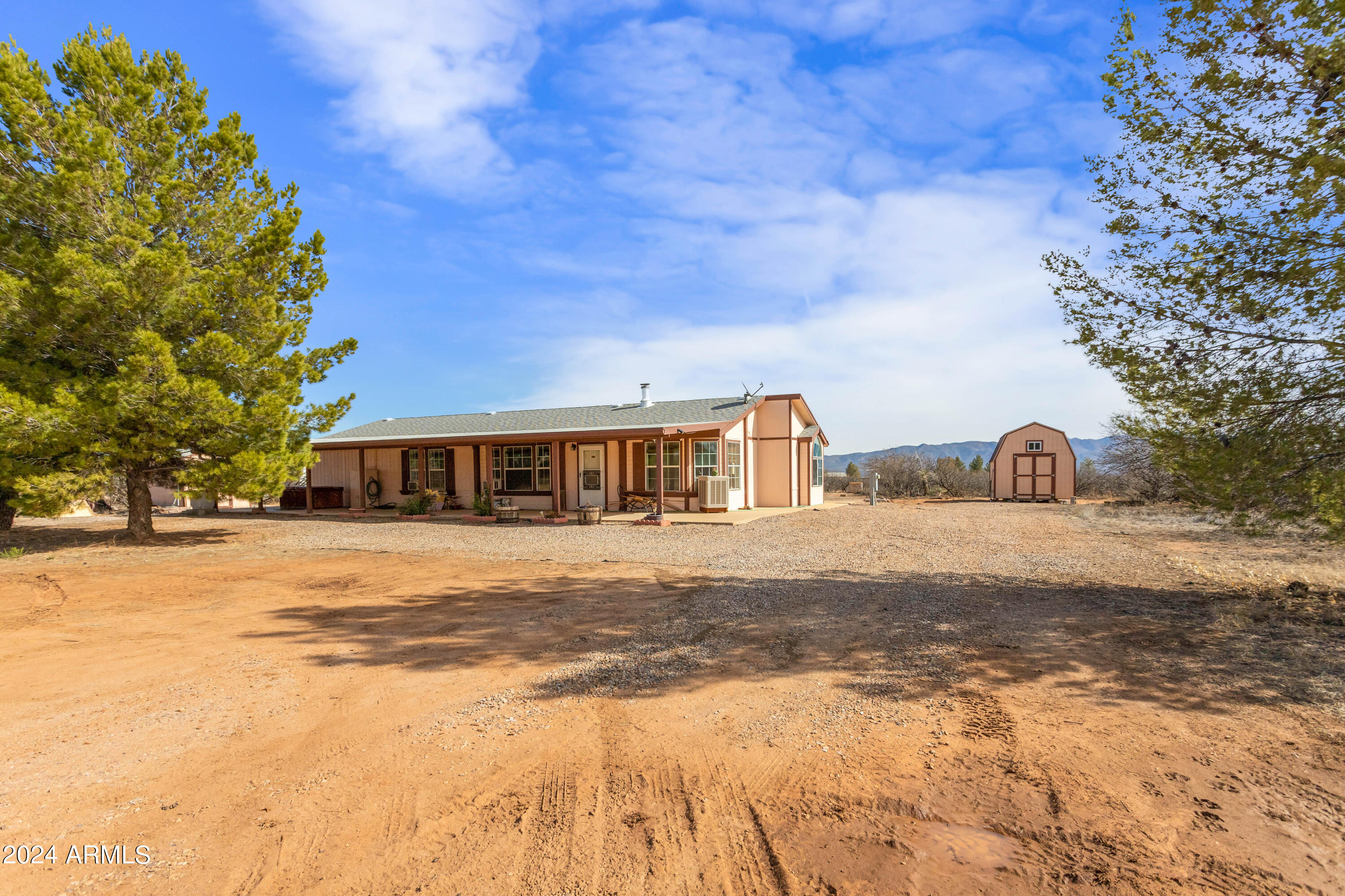 Welcome to your own slice of paradise! Nestled on just under 4 acres of land, this charming manufactured home boasts breathtaking views in every direction. The property is fully fenced and crossed fenced, providing privacy and security. Step inside to discover a cozy yet spacious interior featuring 3 bedrooms & 2 bathrooms. Enjoy convenience of an eat-in dining area as well as formal dining room, perfect for entertaining or hosting family dinners. Outside, you'll find three sheds and 2 car garage offering ample storage space. Enjoy the Arizona sunsets on your large covered porch over looking the mountains while in your rocking chair or hot tub also on the porch. RV parking on North side of house with hookups.
