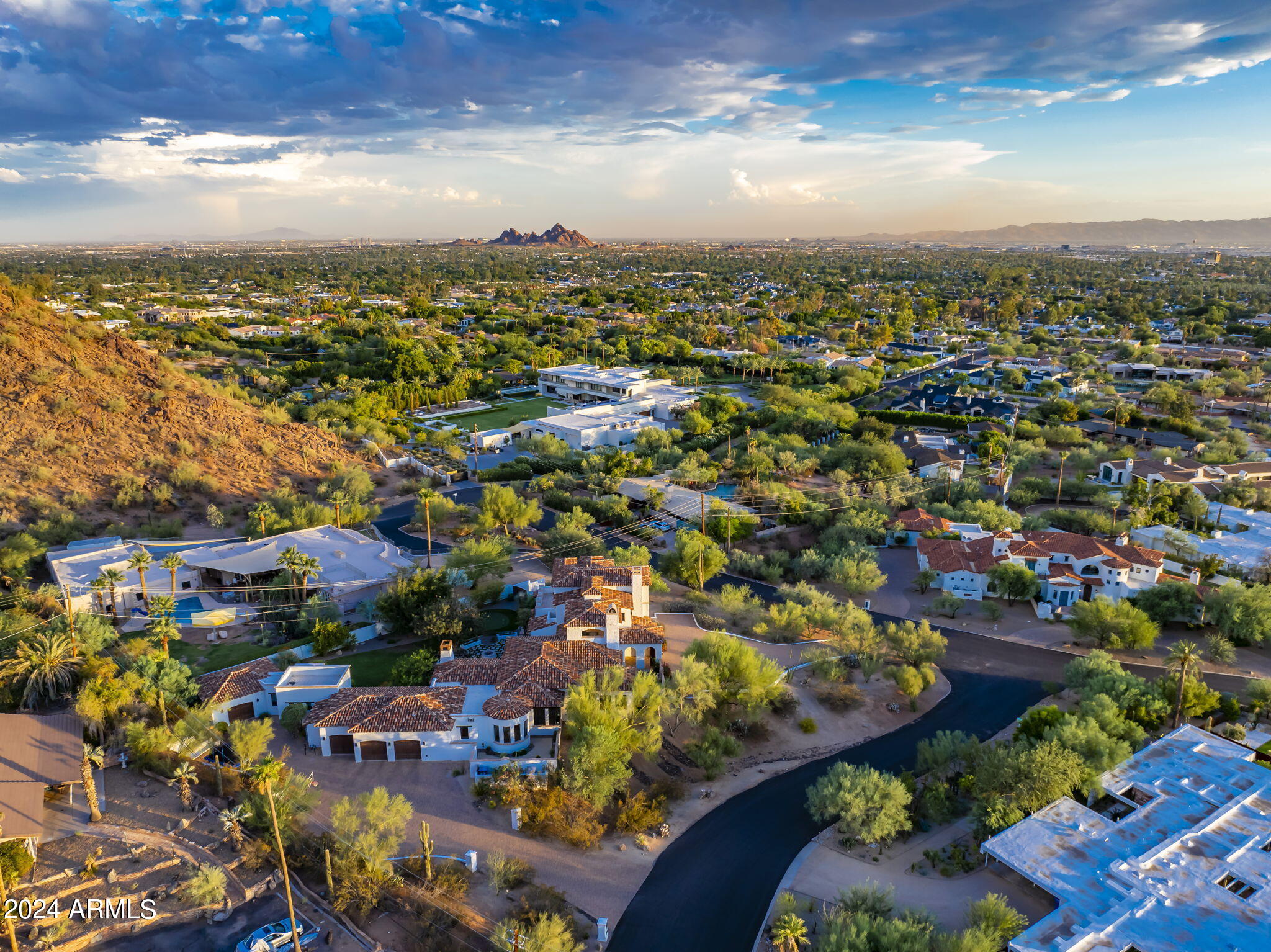 Welcome to White Gates, an elevated Arcadia Hillside acre estate, located in the glow of Camelback Mtn with city skyline & sunset views. Built ground up with the highest attention to detail, quality construction & the intention of capturing gorgeous views in every room, this home has it all. This nearly 6200 SF home was recently renovated in 2022 with a fresh design & luxury interior that seamlessly blends a calm CA feel while embracing the beauty of the AZ desert. You'll feel worlds away from the hustle in this private Santa Barbara style 5 bedroom 5 bath home, located in Hopi school district on the south slope of Camelback. Arrive to find the most welcoming arched front entry & private landscaped courtyard featuring detailed brick ceilings, herringbone pavers & one of 5 fireplaces. Enter through a grand arched wooden door to find a Foyer featuring a floor to ceiling arched window revealing views of Camelback Mtn, a gorgeous fountain & green manicured backyard. The Living room with gorgeous wood beams, wood floors, floor to ceiling French doors & a stately Canterra fireplace opens up to the bright & beautiful Family Room. The main house offers 4 bedrooms, 4 baths, a formal Living Room, formal Dining Room, Family Room, Bar, 800 bottle temperature controlled Wine Cellar, elevated designer Kitchen & round Breakfast Room w north courtyard access, Pantry, spacious Theater, two covered terraces for outdoor entertainment & two custom Laundry Rooms. Each oversized bedroom has its own private  view plus rich wooden French doors, custom curtains, high ceilings, wood floors & walk-in closets. City skyline & Camelback Mtn views are absolutely unmatched from the hotel style Primary Suite, a serene room with cathedral ceilings, custom lighting, custom curtains, gas fireplace, TV, coffee bar, walk-in custom closet, flex office space & laundry room. Experience unparalleled city views from the newly renovated Primary Bath, offering two vanities, large vanity mirrors, custom lighting, tiled floors, tiled walk-in shower & a spacious Kohler bathtub w brass hardware. You can wow your friends in the covered outdoor view Terrace which captures 360 degree views and offers the best entertainment around the outdoor gas fireplace, TV & outdoor bar. Enjoy more Camelback views from the Dining Room, the Kitchen, the Breakfast Room & even the Laundry Room. The Kitchen comes fully loaded with an oversized granite island, travertine floors, high-end stainless appliances, 2 dishwashers, a 6 burner gas range, double ovens, custom Canterra hood, 2 beverage drawers, a built-in warming drawer & microwave, 2 sinks, custom cabinetry, 3 pull out trash cans & a built-in breakfront perfect for your china. Off the Kitchen, you'll find a fabulous beamed outdoor dining space with gas fireplace & a fabulous outdoor Kitchen featuring a Green Egg smoker, large 4 section infrared grill, built-in beverage cooler, sink, lighting & counter seating.  Walk through the covered breezeway to the attached one bedroom one bathroom Casita which is well equipped with it's own spacious bathroom, kitchenette, walk-in closet, storage closet & separate 1 car garage. Putt & chip on the new turf putting green, sit under the trees by the fire pit or enjoy ping pong in the outdoor covered game area. Two separate paver driveways allow for a grand front entrance & a side motor court entry to the 4 car garage w storage cabinets & temperature controlled storage room. Turf, grass & indigenous desert landscaping offer a low maintenance backyard with less water usage. Security cameras throughout. This incredibly special estate is one of a kind & truly offers an unparalleled tranquil experience of sunrises & sunsets that will make you fall in love.