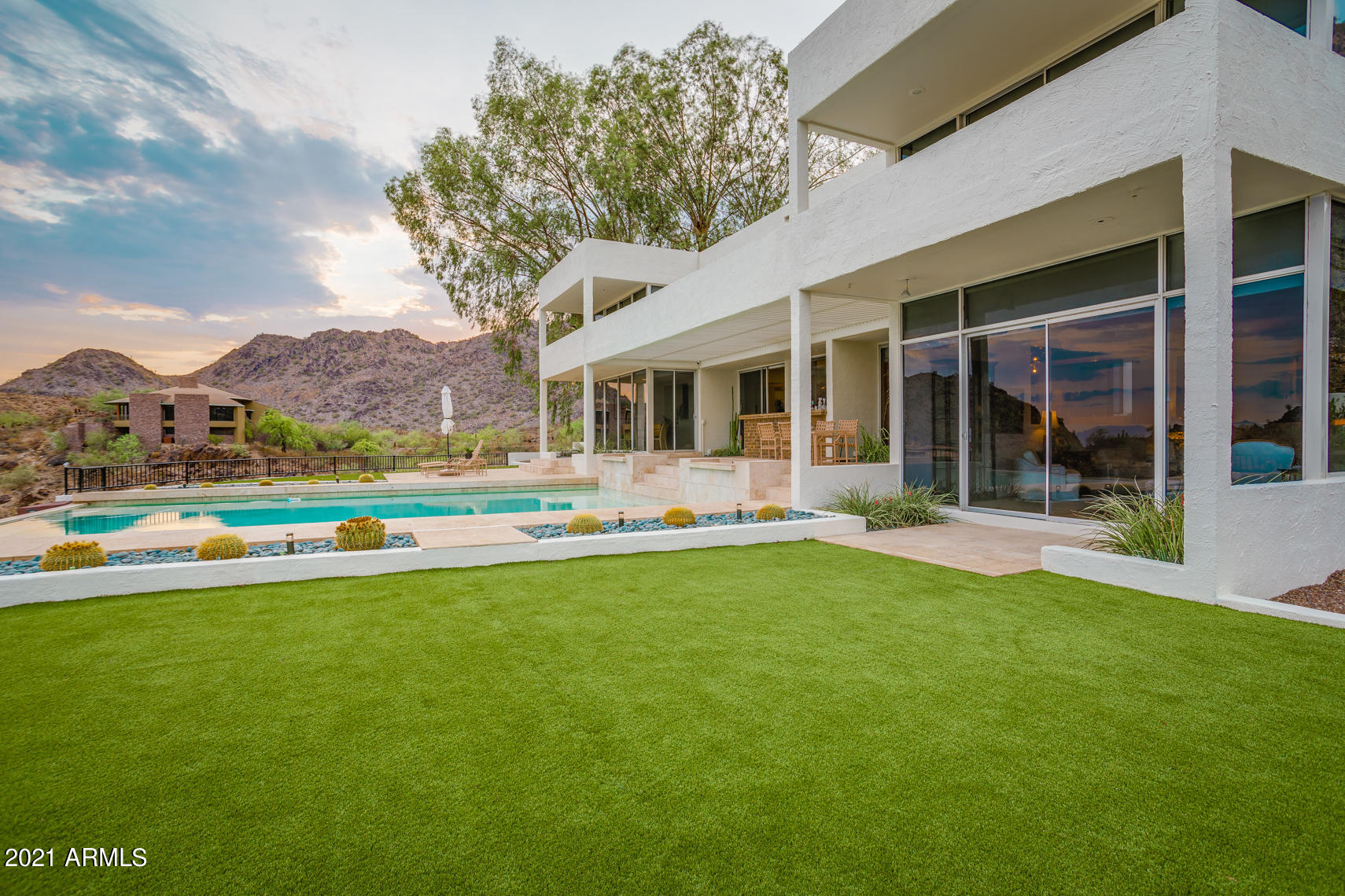 WOW! Modern Hillside home designed by Ned Sawyer FAIA. Spectacular views couple w/superb architecture. Positioned near top of Palm Canyon, home commands the site w/sweeping vistas of surrounding mountains and city lights! Desert modern mortar-washed masonry is juxtaposed against the crisp lines of the house. Versatile plan includes: 5 BR's, guest suite, office/den, formal dining, Lrg living room, built-in bar, lux eat-in kitchen w/upgraded appliances. Views from nearly every room! Outdoor living perfect for entertaining; oversized patios, negative edge pool, synthetic grass yards. Hillside gains the views, but flat yard offers generous space. Located between PV and Biltmore, Palm Canyon offers fantastic location w/an array of original designs Will Bruder to Frank Lloyd Wright! ACT NOW!