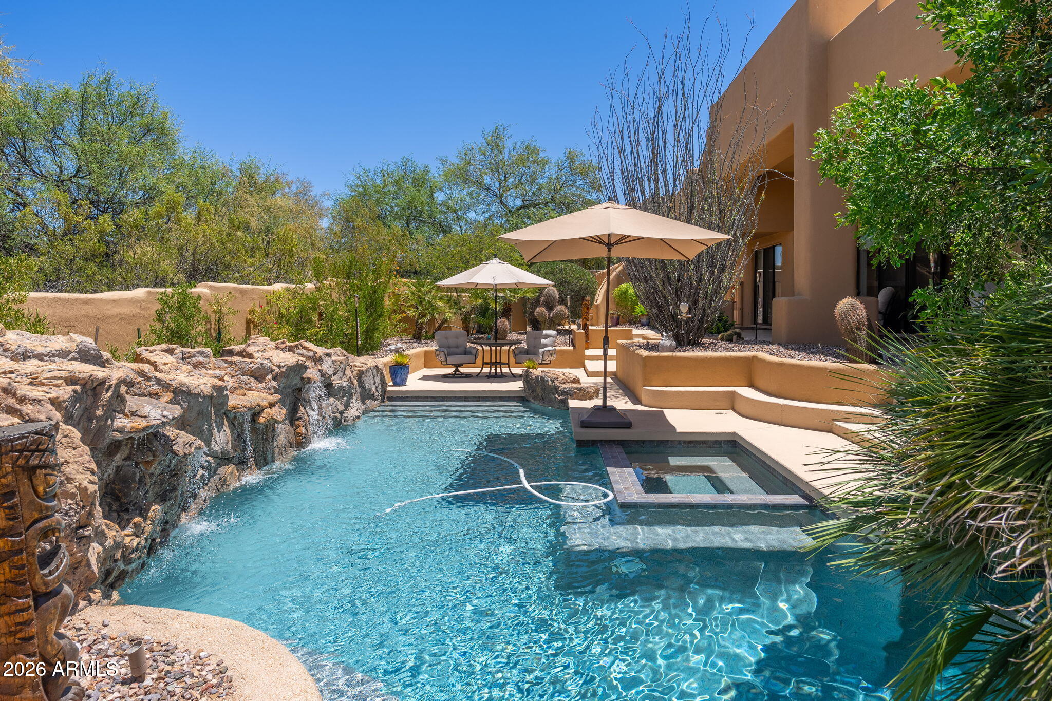 Nestled on a quiet cul-de-sac within the guard-gated community of Candlewood at Troon North, this thoughtfully updated residence offers the perfect blend of privacy, comfort, and Sonoran Desert beauty. The lush backyard retreat is designed for year-round enjoyment, featuring a sparkling pool framed by natural boulder accents and a waterfall feature, a heated spa, and an elevated covered patio spanning the length of the home for effortless outdoor living and entertaining.

The flexible floor plan provides exceptional separation of space. The primary suite occupies its own private upper-level retreat complete with a balcony, wet bar, spacious bath, and walk-in closet, accessed through a loft with an additional balcony overlooking the property. A downstairs bedroom and adjoining sitting room with a private front patio offer ideal guest quarters, multigenerational living, home office space, or the potential for dual guest suites with a shared bath. Two additional guest bedrooms are located on the opposite wing of the home.

At the center of the residence, the great room and kitchen (remodeled in 2023) create a welcoming gathering space highlighted by natural slate flooring, beam accents, clerestory windows, a built-in entertainment center, wet bar with wine refrigerator, walk-in pantry, breakfast nook, center island, and large picture windows that fill the home with natural light. Recent kitchen updates include refreshed cabinetry, granite countertops, updated appliances, sink, hardware, and fixtures.

Extensively improved and meticulously maintained, notable upgrades completed between recently include a new roof (2023), three HVAC systems (2022), pool equipment (2022), interior and exterior paint (2022 & 2024), patio deck (2025), water filtration system, updated plumbing fixtures, lighting (2022), flooring, window treatments (2024), closet systems, an alarm system, and numerous additional interior enhancements.

Additional features include block construction, sand-finish stucco exterior, side-entry three-car garage, elevated lot, generous laundry room with storage and utility sink, and abundant architectural character throughout. Located just minutes from several of Scottsdale's premier golf courses and within walking distance of hiking, biking, and equestrian trails, this is Troon North living at its finest.