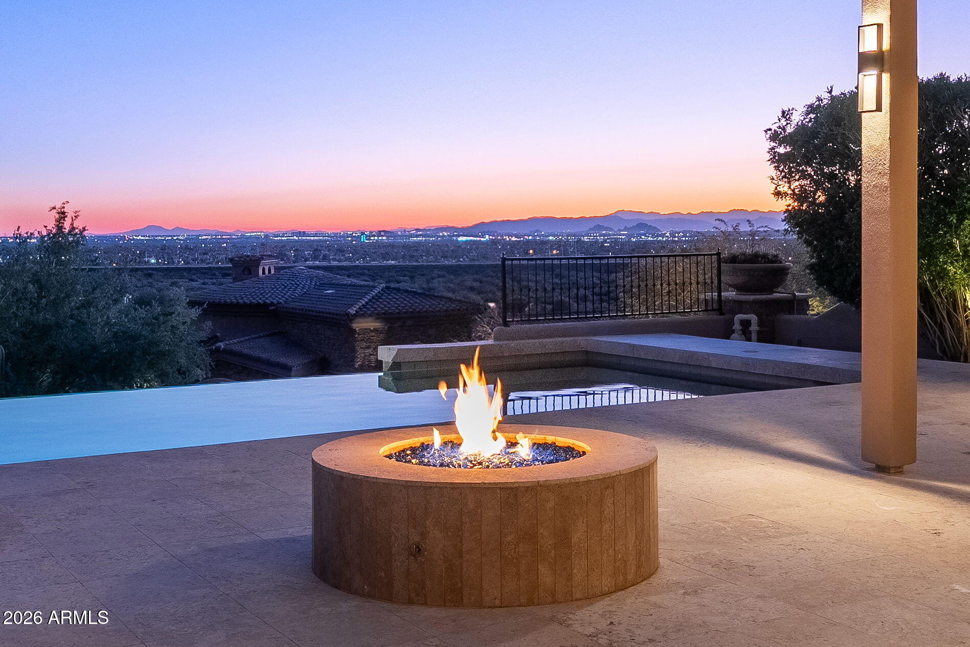 Perched atop the hillside within the guard gated Ancala Country Club, this extraordinary custom estate commands sweeping, unobstructed views of Camelback Mountain, city lights, and desert horizons. Set on nearly an acre, this 4 Bedroom: 6 Bathroom plus office residence offers a rare blend of timeless architecture, refined craftsmanship, and breathtaking scenery from nearly every vantage point. Upon entry, disappearing 9-foot sliding glass doors in the living room create a seamless indoor-outdoor living experience, ideal for sophisticated entertaining. Designed with classic elegance, the home showcases traditional details throughout, including soaring 13-foot arched windows that beautifully frame the surrounding landscape. The primary suite, ideally located on the main living level, opens to the upper covered balcony for easy access. Every bedroom is thoughtfully appointed with en-suite baths, including a guest suite on the main level. Also on the main level an exquisite library/office featuring rich alder millwork and private views of the mountain behind the home. The chef's kitchen is adorned with natural stone and equipped with Wolf and Sub-Zero appliances, including a 48" gas range, double ovens, double Asko dishwashers, a walk-in pantry, and breakfast nook all overlooking the family room and glittering city views beyond. Designed for memorable gatherings, the home features a 700+ bottle wine cellar with a circular wet bar, an ideal setting for entertaining while watching the sun dip below the horizon. The lower-level hosts two additional guest suites, one with a large sitting area, a home gym, and media room with McIntosh surround sound, complemented by a large wet bar: kitchenette area and 2nd laundry all with custom millwork throughout. Ideal for teenagers or multi-generational living. Outdoors, resort-style amenities await: a lower expansive patio with BBQ island, sparkling pool and spa, firepit, outdoor shower, pergola and multiple spaces to relax and entertain all framed by the home's incredible elevated views. A regular sized elevator provides ease of access to all levels. This estate is completed by two separate two-car garages, including a lower-level garage ideal for guests and additional parking.  The upper-level garage with driveway space to turn around, and additional parking allows direct access to the main living areas. All HVAC units have been replaced as well as water heaters. See documents tab for all upgrades! This home has been meticulously cared for. The country club and golf course are accessible through private membership