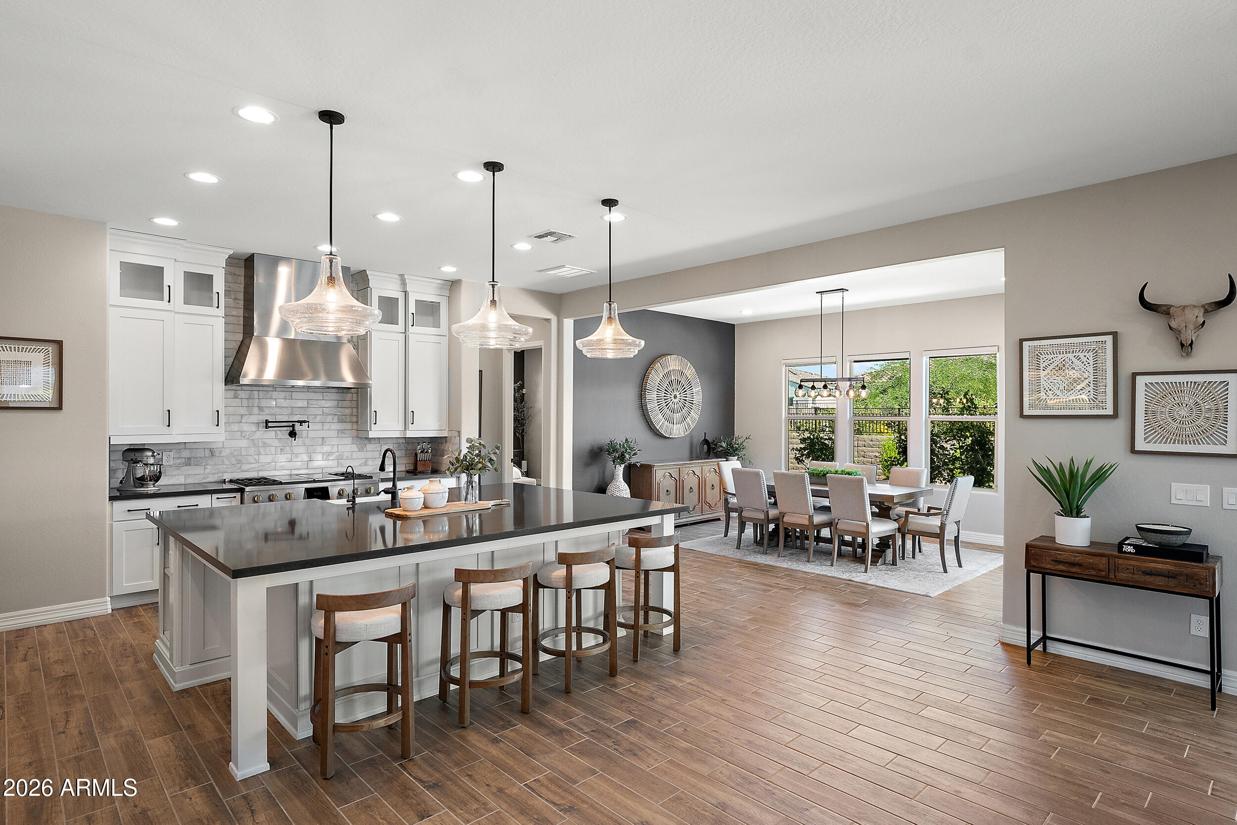 Tucked behind the gates of the Estates at Eastmark, this refined single-level residence blends style, comfort, and modern Arizona living in one of Mesa's most desirable communities. Built in 2022 and showcasing over $200k in premium upgrades, every detail of this home was thoughtfully curated for elevated everyday living, with an abundance of well-designed storage throughout.
Inside, soaring 10-foot ceilings, expansive wood-look tile flooring, and an abundance of natural light that enhances the home's sophisticated open-concept design. At the heart of the home, the chef-inspired gourmet kitchen is a true showpiece, featuring striking quartz countertops, a dramatic oversized island with seating, stacked maple cabinetry, and premium 48'' Monogram stainless steel appliances complete with a a professional-grade hood and pot filler.
Designed for seamless indoor-outdoor living, the expansive great room opens effortlessly through a stunning 3-panel sliding glass wall to the covered travertine patio, where automatic sunshades create year-round comfort. The backyard retreat is equally impressive, offering an extended patio, custom gazebo, built-in BBQ, fire pit, ambient globe lighting, and view fencing overlooking the scenic trail behind the property -- creating a peaceful and private backdrop for entertaining or enjoying striking views of the Superstition Mountains.
The primary suite offers a relaxing retreat with a spa-style bath featuring dual vanities, a clawfoot soaking tub, oversized walk-in shower, and spacious walk-in closet. Secondary bedrooms are generously sized, each featuring its own full bathroom and walk-in closet for added comfort and privacy.
Additional highlights include:
" Dual 2-car garages with epoxy flooring, built-in cabinetry, direct-access, keyless entry, EV charger, and garage service door.
" Laundry room with built-in cabinetry and utility sink concealed behind a barn door
" Exterior sunshades on the east side of the home for enhanced energy efficiency 
" Private home office/den highlighted by classic double doors and extensive built-in cabinetry for seamless, organized storage

Residents of the Estates at Eastmark enjoy private access to community amenities including resort-style pool, parks, walking trails, clubhouse, and vibrant community spaces.

A rare opportunity that truly must be experienced in person.