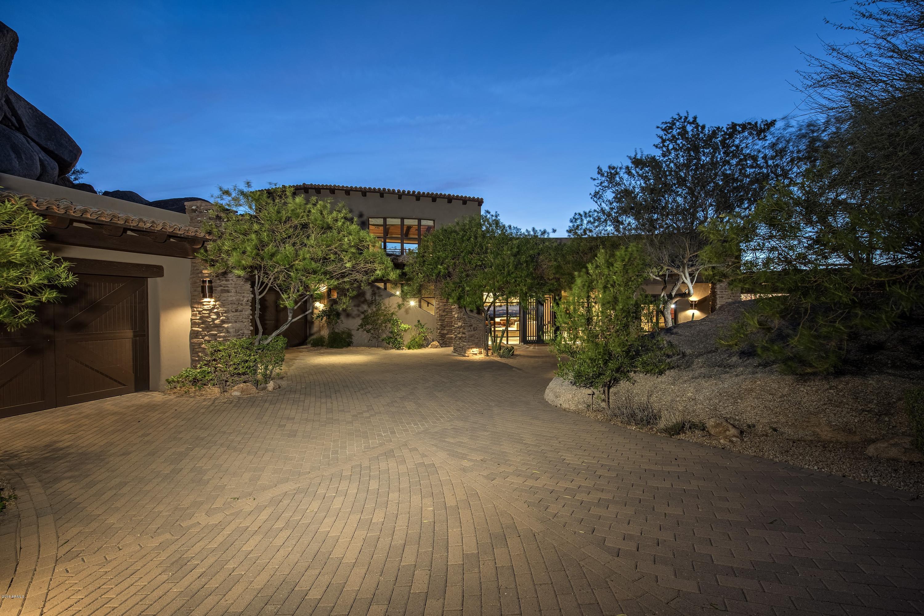 Nestled amongst the boulder formations of Troon Mountain featuring panoramic city skyline views, sunsets & city lights sits an exquisite southwest contemporary home. A large living room featuring telescoping patio doors offering indoor-outdoor living, a large bar & 2-way stone fireplace for entertaining welcomes you in. Gourmet kitchen offers Viking, SubZero & Asko appliances and opens to the family room & breakfast nook. A covered bridge provides access to the large guest house offering a family room, kitchen, bedroom & game room.  Sweeping views from the backyard patio offer free form swimming pool, therapeutic spa, cascading waterfall, fireplace & Barbeque/bar area.  Slate flooring, 3-inch chiseled edge stone & granite countertops, custom stone details & wood features throughout.