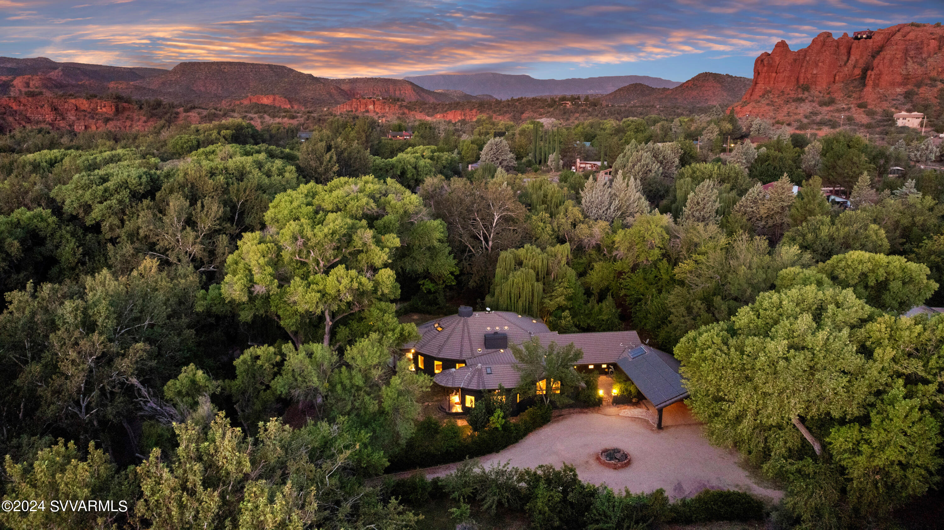 This one will take your breath away. From the moment the stoned  private gates open you are transported to a fairy book oasis brimming with aquatic ponds, orchards, towering cottonwoods, running water through a historic ditch canal and a sprawling  estate aptly named the Sanctuary. Cradled on 6 acres close to the river of Oak Creek, this 4-bedroom home unfolds with unique beauty. From the towering 52 x 26-foot crescent shaped great room boasting recycled leather flooring, a massive red stone etched  wood burning fireplace  designed for a cooking cauldron, padauk hardwood windowsills to this estate's  4 aquatic wildlife interconnected ponds  filled by protected water rights  this refuge is truly one of a kind. The 6 acres are a mixture of enchanting woods and groves of flowering trees and and on any given evening you will see baby deer nestled, herons  on the ponds or hear the whispering of the cottonwood trees. An original winery shed of one of the founding families of Sedona is nestled  on the grounds and   could be showcased as a  Vinter Shed as with the 700 foot private well and the deeded protected water rights  this land is ripe for a the viticulture enthusiast, small crop agriculture farmer,  organic gardener, or as a spiritual retreat refuge.  5172 square foot main home welcomes you in with its wood beamed rafted ceilings, travertine stone flooring, 3 fireplaces dotted throughout the great room, living room and large office which could be an additional sleeping quarters. Kitchen is warm and inviting with warm accented wood cabinetry, impressive formal dining room boasting an  English dining table dating back to the 17th century adds to the charm as this home is being offered completely furnished except for a few personal family items. Mirrored yoga/exercise room, pass through library, 3 bedrooms, full guest bath and powder room with marble vessel sinks add to the allure. Primary bedroom ensuite, great room, office, and dining room all open onto half-moon circular covered cement patios that spill out onto your impressive grounds offering flagstone open aired patios, 1600 square foot vineyard, 2500 square foot garden, orchards, myriad wooden bridges, and stone pathways over and next to running water, and fruit trees galore! All with irrigated water piping reaching all 4 corners of the property, the land is ready for you to create your own sanctuary. Additional features include  lower basement climate-controlled wine cellar currently used as storage, 84 paneled solar power system, highlighted water wheel, circular driveway, covered carport, and additional covered parking. 1352 square foot 2 story RV and 3 car Garage workshop with its own separate permitted septic tank and field could easily be converted into an additional guest quarters. This enchanting family estate was envisioned and designed to be an oasis far from the maddening world, a place to take refuge, to find solace amongst nature with nature, a synergistic sanctuary. This one will whisper to you, will wrap you up in it's charm and call you home.