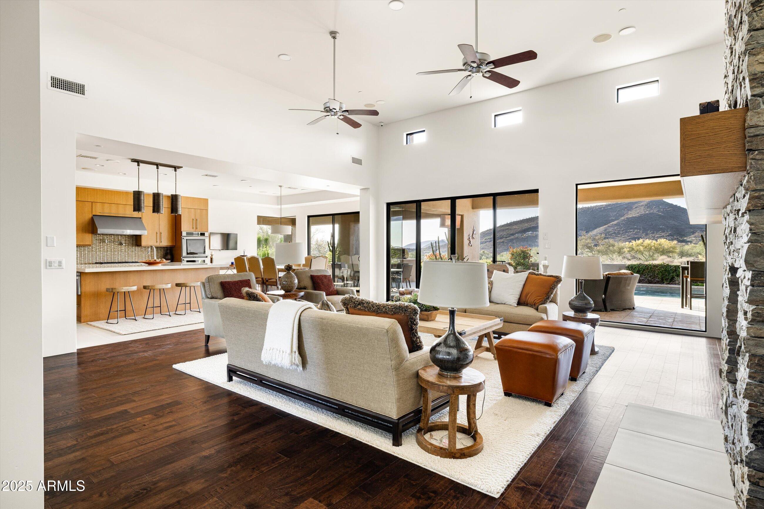 Soaring ceilings and walls of glass that open up to panoramic views of the mountains, sunsets and surrounding Sonoran Desert landscape. The spacious great room features a striking stone fireplace and leads into a chef-inspired kitchen equipped with top-of-the-line appliances, custom cabinetry, and a large center island—ideal for both cooking and entertaining.
The luxurious primary suites offer the perfect sanctuary with its private terrace, spa-like baths one  with soaking tub and dual vanities, and patios.  Each additional bedroom is en-suite, offering comfort and privacy for family and guests. The spacious office with closet and adjacent bath make the option for a  fifth bedroom.   Outside to a resort-style backyard where relaxation meets recreation. The sparkling pool and spa, the built-in barbecue and multiple seating areas make it an entertainer's paradise, the space is perfect for both tranquil moments and lively gatherings.
Located within Desert Mountain, a private enclave known for world-class golf, fine dining, and unparalleled amenities, this property offers not just a home, but a lifestyle.  Membership wait list apply.