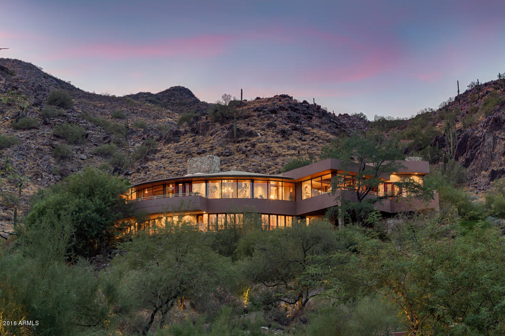 Named the Golden Nugget Award Winner ''Best in the West'', this very private curvilinear residence is built to capture mountain breezes and outstanding CITY LIGHT and MOUNTAIN VIEWS! Using native stone that is dry stacked to be more natural, 270 degrees of glass view walls and interior wood finishes,it feels a oneness with the mountain. Cherrywood floors, custom wood cabinetry and intricate ceilings exude a feeling of warmth. Open and light and very alluring, this 4 bedroom plus library home also features a pool with waterfall and stepping stones set against the mountain, an exercise room, and important for car lovers-- a 5 (or 6) car garage plus a huge parking outdoor courtya