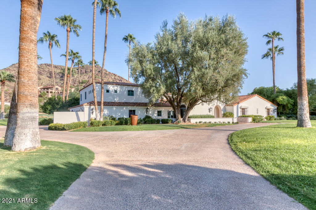 Backing to Paradise Valley Golf Course on a quiet cul-de-sac street is an absolutely charming Santa Barbara home designed by George Christensen. The flat 1.13-acre lot boasts  Camelback Mtn, Mummy Mtn expansive lawns + Golf Course views. Set back from the street with a circular drive, the front of the home is exceptionally beautiful. An arched entry welcomes you inside to a magnificent 16 ft high great room with beamed ceilings and a tall arched window overlooking the grounds + golf course. The main home has a private office off the entrance, a lofted study, 3 ensuite bedrooms, and a warm and inviting kitchen with an intimate family room. There is an attached 2nd floor guest house with living room and 4th bedrm.  the home is filled with natural light!