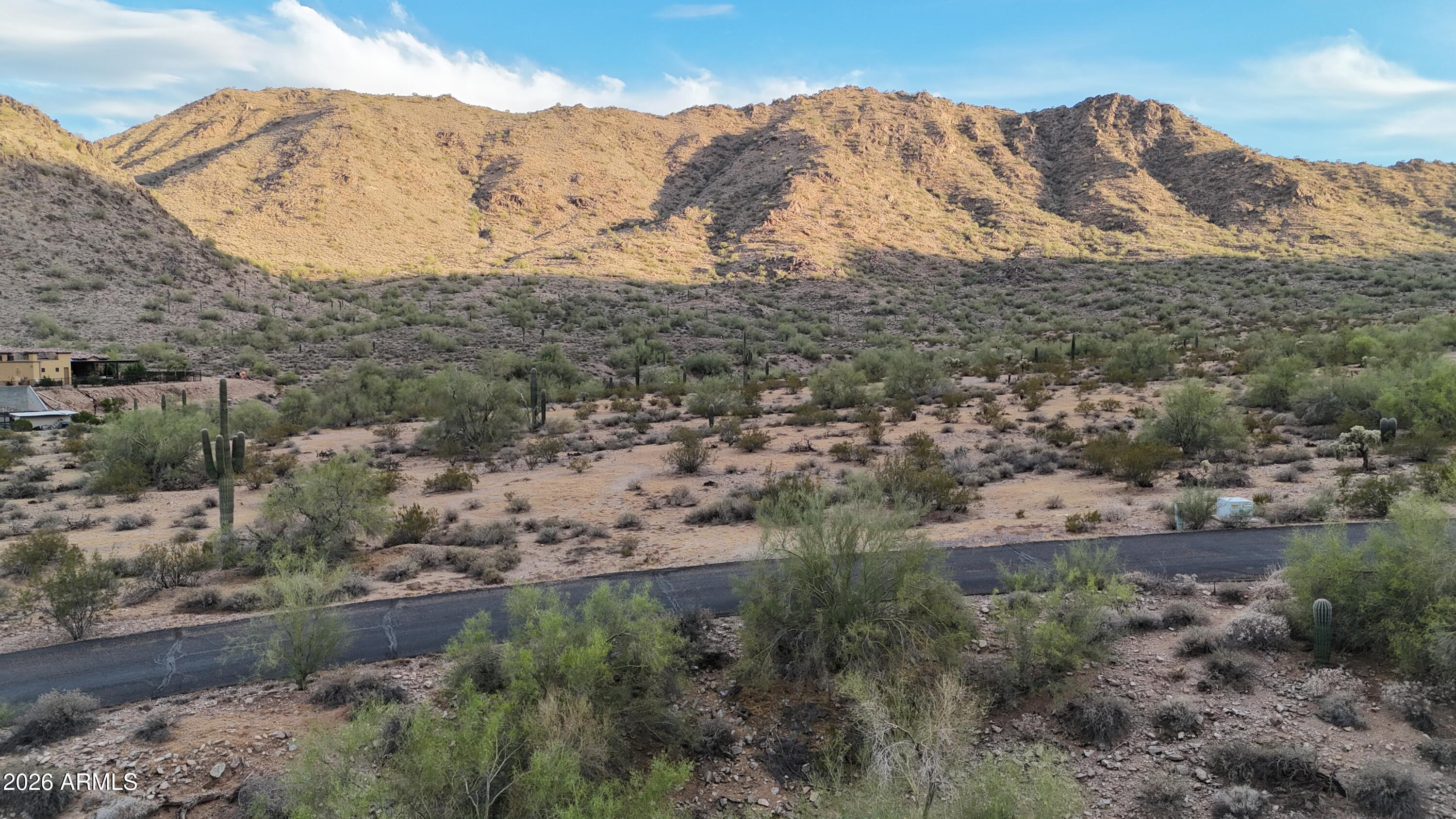 Escape to one of Queen Creek's most distinctive homesites. This parcel is cradled in a private mountain cove at the end of a well maintained paved road, an elevated corner lot next to the rugged Sonoran foothills and offers unmatched seclusion while remaining just minutes from the conveniences of town.
Wake up to dramatic mountain ridgelines in every direction. Step outside and take in panoramic views stretching across the valley to the Superstition Mountains and twinkling city lights at night. Towering saguaros, mature palo verdes, and natural desert vegetation are already established across the property, giving your future home instant character and a true Arizona sense of place.
What makes this lot special is the rare combination of attributes you'll find here. It sits on a quiet corner at the mountain's edge, with elevated hillside topography that opens up commanding 360 degree views of mountains, desert, city, and city lights. A maintained asphalt road runs right to the property. City water and SRP electric are already at the lot, and a natural wash on the parcel adds character and handles desert drainage. There is no HOA, so you're free to build your vision your way, and you'll be surrounded by high end custom homes in an established enclave.
Whether you're planning a hillside contemporary, a sprawling hacienda, or a walkout design that takes full advantage of the view corridor, this lot delivers the canvas. It's the kind of setting that feels a world away, yet you're still close to Queen Creek shopping, dining, and top rated amenities.
Lots like this, with utilities, paved access, established neighbors, and true mountain privacy, rarely come available. Come walk the land and imagine the possibilities.
Owner/Agent.