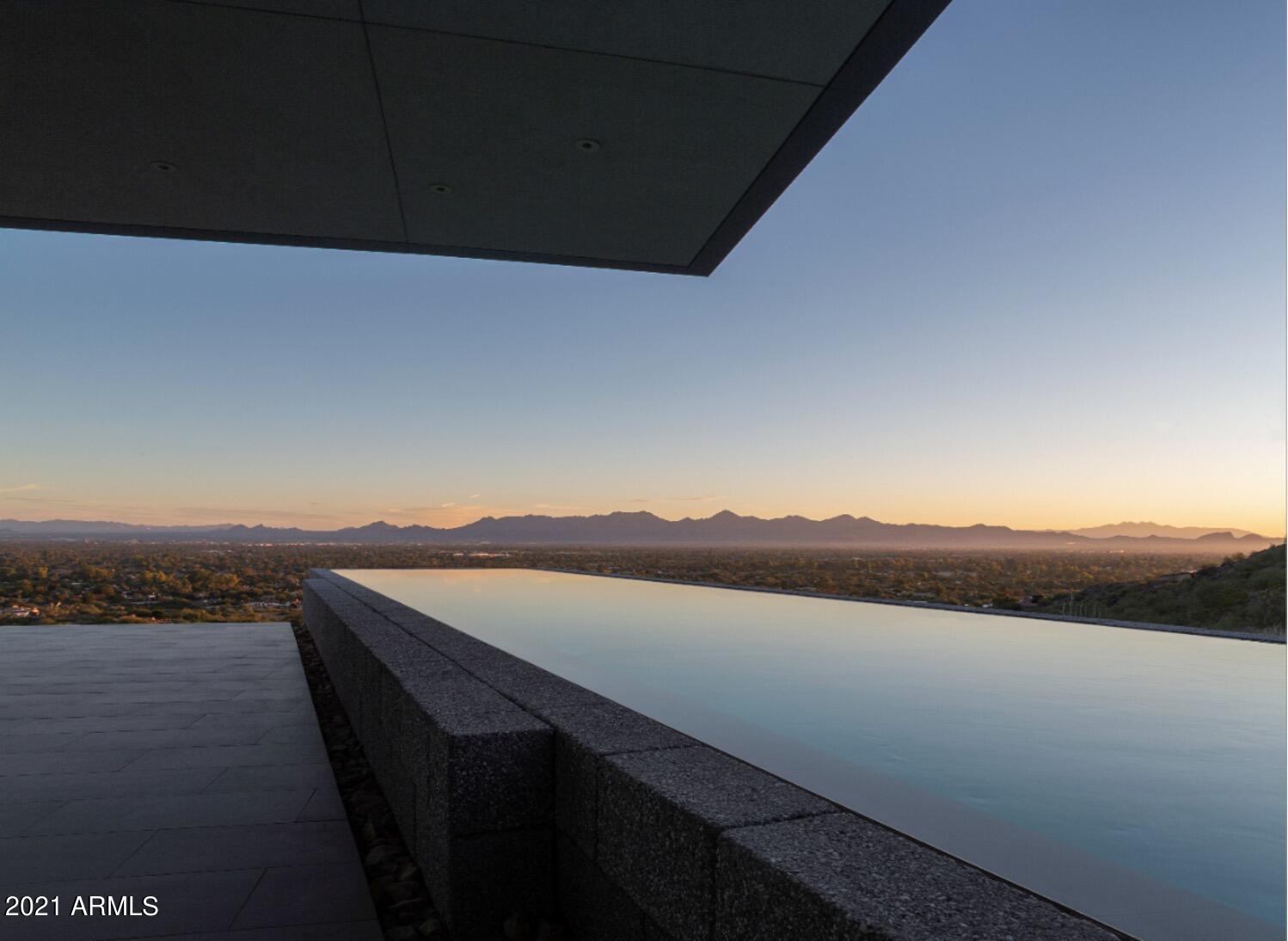 This single level modern masterpiece was three years in the making with an unmatched attention to detail. The artistry in creating this elegant, soft warm contemporary home exudes taste making at its finest. Resting on a spectacular hillside site with stunning views and privacy, the large interior & exterior expansive spaces live without any stairs and a nearly zero grade gated driveway. The architectural features are stunning; the 85' wing roof, a disappearing bar, a pool cantilevered out over the mountain's edge and more. The home is truly a spectacle for the senses and at night, the sunset colors of the mountains reveal the sparkling lights of the city below. The quality of design coupled with the best materials and finishes are combined in the creation of a striking and beautiful home.