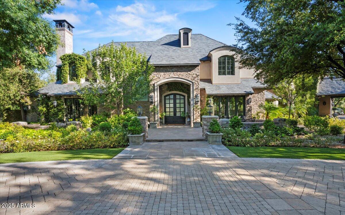 Situated on more than two acres of land, this exquisite property offers seven ensuite bedrooms, eight bathrooms, an impressive six-car garage with a carriage house and motor court, and more than eleven thousand square feet of luxury living. Created by one of Arizona's premier builders, Calvis Wyant, the custom design offers endless luxurious quality. Built to accommodate informal family breakfasts as well as large dinner parties, the chef's kitchen has double islands, double ovens, two sinks and two dishwashers. Floor to ceiling windows in the formal living room provide a setting like no other overlooking grounds that are arguably the most magnificent in the entire city. The dining room has a beautiful reverse groin vaulted ceiling, and the master retreat is high end living at its finest with soaring ceilings, informal sitting areas, fully retractable glass doors and a charming fireplace that add refined elegance to this dream worthy space. The professional office has truly inspired design elements, there are multiple living rooms including a game room, the home theater has comfortable seating for eight, and there are three fully stocked wet bars. The outdoor kitchen allows for convenient service to guests on the patio, and the property's numerous sports amenities will get your heart pumping featuring a workout room, sauna, heated pool and spa, and par three golf hole with a real sand bunker. Night game? Of course, just turn on the lights! There's a detached ...