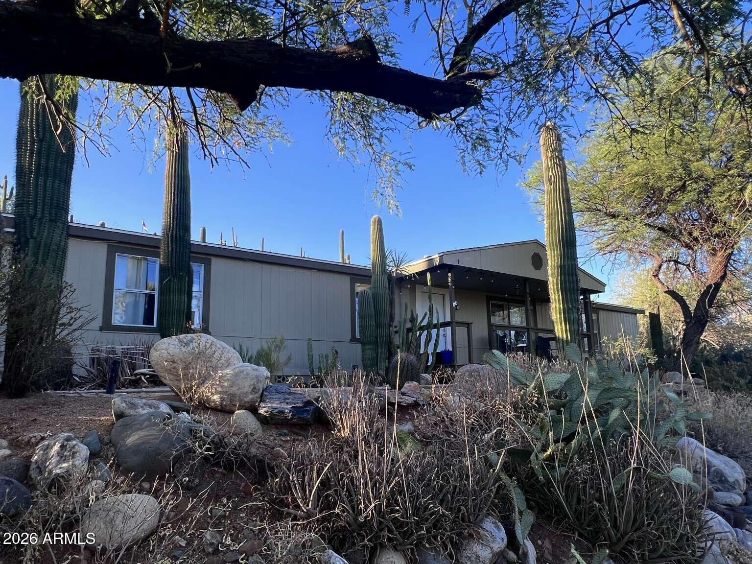 Exceptional privacy & panoramic valley views define this permanently affixed 3/2 home on an elevated Black Canyon City hillside. Enjoy wide open space, generous distance from neighbors, & a low-maintenance yard with towering Saguaros. Inside, the 1,782 sq ft layout has modern flooring, a master suite with a soaking tub, & a cozy wood-burning fireplace with a mounted 75'' TV included. The bright kitchen features custom white cabinets & updated stainless appliances (GE gas range/Bosch dishwasher). The oversized 2.5-car garage is finished & insulated, with a LiftMaster opener, checkerboard flooring, workbench & shelving, & older wall AC (as-is). A large shed stays, plus an outbuilding frame ready to customize into a chicken coop, catio, or aviary. Covered view deck.