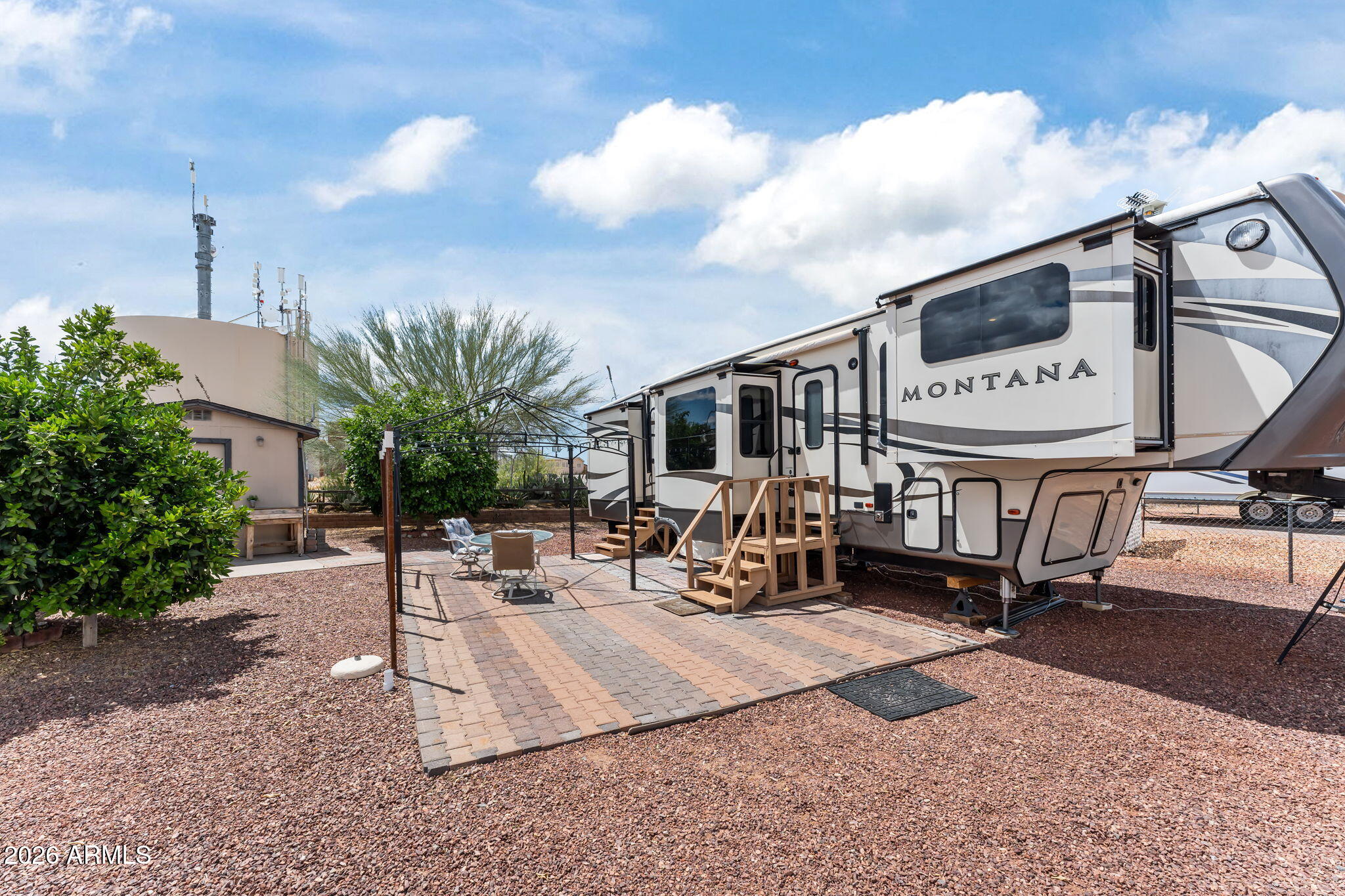 Live the ultimate Arizona RV lifestyle under endless blue skies! This OWNED, fully fenced lot offers privacy, tranquility, and room for your furry companions, all framed by breathtaking mountain views. Unwind on your private patio surrounded by lush, irrigated citrus trees--orange, grapefruit, and lemon--for that perfect desert morning. This lot is ideally nestled with no homes in front or behind. Enjoy direct access out your back gate to the Pickleball Barn, or stroll across to the Community Center. A short distance to miles of open State Trust land--perfect for adventure and tranquility. The spacious Fifth Wheel shown is available for purchase with a separate bill of sale.  Minimal HOA fees and NO AGE RESTRICTION makes this land within reach to start living your dream!