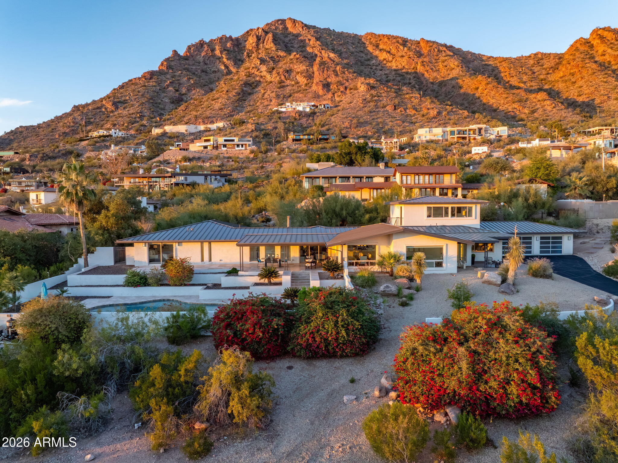 Perched on the coveted south side of Camelback Mountain, this modern-contemporary estate captures sweeping 180-degree city lights, Papago and South Mountain views, vibrant sunsets, and glowing sunrises with Camelback as your dramatic backdrop. Light-filled interiors feature a white chef's kitchen with island and bar seating, Sub-Zero and Wolf appliances, opening to expansive living areas with fireplace and walls of glass framing the views. Offering 4 bedrooms, 3.5 baths, large his-and-hers walk-in closets, and a private-entry guest casita with views. Theater room, Control4 smart home, dual driveways, 3-car garage with Tesla charger and storage. Entertaining home w/ heated pool and easy lock-and-leave living. Minutes to PV, Arcadia, Old Town, Downtown Phoenix, and 15 minutes to Sky Harbor. The ideal view home with views stretching across Arcadia, Papago, Scottsdale, and the Downtown Phoenix skyline. Ideally positioned just minutes from the premier dining, shopping, and lifestyle destinations of Arcadia, Scottsdale, and Paradise Valley and Sky Harbor Airport.