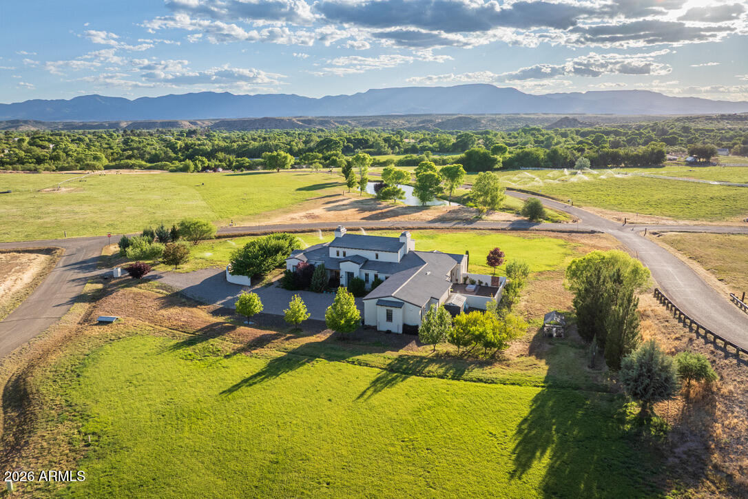Some places change your address. Others change your pace. There's something magical about Green Belt living. Cattle graze in open pastures, shimmering water reflects the changing sky, and sunsets linger. Set on 2.06 irrigated acres in gated Rio Bonito Ranch, this exceptional Modern Farmhouse is the essence of luxe country living. Surrounded by green space, walking paths, and panoramic views, the 2,941 SF residence offers 3 BD | 3.5 BA, drenched in natural light, soaring 18' ceilings, exposed wood beams + a spectacular screened patio overlooking open countryside, water views, and the Mingus Mountains beyond. With Oak Creek, private beaches, and miles of trails moments away, this is more than a home--it is a daily invitation to slow down, reconnect, and savor the moments that matter most. Beyond the gates of Rio Bonito Ranch, life unfolds at a gentler pace. Morning walks wind through emerald pastures as deer move quietly among the cottonwoods. Residents enjoy private beaches along Oak Creek, expansive recreational areas, walking paths, paved roads, and a rare connection to the land that feels increasingly difficult to find. As evening settles in, the ponds and pastures are bathed in the colors of spectacular Verde Valley sunsets.

Despite its peaceful setting, everyday conveniences remain close at hand. The acclaimed wineries of Page Springs are just minutes away, along with local favorites including Manzanita, Up The Creek Bistro, G's Burgers, Brewha, and the Windmill Park Cornville Farmer's Market. Sedona's iconic red rocks are approximately 15 miles away, while Cottonwood's vibrant Old Town, I-17, Flagstaff, and Phoenix remain easily accessible.

Built in 2018, this exceptional residence blends modern farmhouse design with thoughtful craftsmanship and timeless appeal. Large-plank porcelain wood tile flooring flows throughout the residence, while vaulted ceilings, substantial wood beams, and expansive glass create an atmosphere that feels both grand and welcoming.

At the heart of the home, the open-concept great room is anchored by a striking Isokern fireplace, flanked by towering built-in art niches that create both a dramatic first impression and a natural feeling of elevated living. It is hard to know where the landscape ends and the home begins. A wall of sliding glass doors opens to the lodge-style screened patio, creating a seamless transition between indoor living spaces and the natural beauty beyond. Rolling pastureland, grazing cattle, visiting wildlife, and ever-changing skies become part of the daily experience.

Designed for both everyday living and effortless entertaining, the chef's kitchen features a Wolf gas cooktop, double ovens, built-in refrigerator and freezer, a substantial center island, abundant cabinetry, and an attached butler's pantry offering exceptional prep space and storage. An oversized pass-through window above the farmhouse sink frames views of lush pastureland, the community pond, and distant mountain vistas while connecting seamlessly to the outdoor covered patio, complete with bar seating and a built-in granite countertop for effortless entertaining and al fresco dining.

The primary suite is a true retreat, where colorful garden blooms, endless green lawn, and the community pond beyond create a serene backdrop for daily living. A cozy sitting area invites quiet mornings with a cup of coffee or afternoons spent with a favorite book. The luxurious en suite bath offers dual vanities, a soaking tub, and a multi-head walk-in shower designed for relaxation. A well-appointed walk-in closet with built-in shelving and drawers is located just across from the bath. Step outside to stroll among fruit trees and native wildflowers before slipping into the private spa to enjoy bubbles, chromotherapy, and complete relaxation beneath open skies.

On the opposite wing of the home, a flexible bonus room provides space for a media room, home office, fitness area, hobby room, or second living room. Two guest suites, each with en suite baths and generous storage, are thoughtfully positioned nearby. A fully fenced side yard with covered patio creates additional space for gardening, pets, or simply enjoying the sunshine.

Beyond the residence, the landscape becomes part of everyday life. The inviting screened-in patio provides a front-row seat to passing wildlife, colorful sunsets, and the ever-changing beauty of the surrounding countryside. Across the property's 2.06 irrigated acres, there is room to garden, gather, play, or simply enjoy the rhythms of Green Belt living. An established fruit orchard, green pastures, valuable ditch irrigation rights, open skies, and a lasting connection to the land create an atmosphere that feels worlds away from the ordinary.

This is a place where seasons are measured by the changing colors of the cottonwoods, where water continues to nourish the land as it has for generations, and where the simple pleasures of nature remain woven into everyday life.

Welcome to life at a different pace.