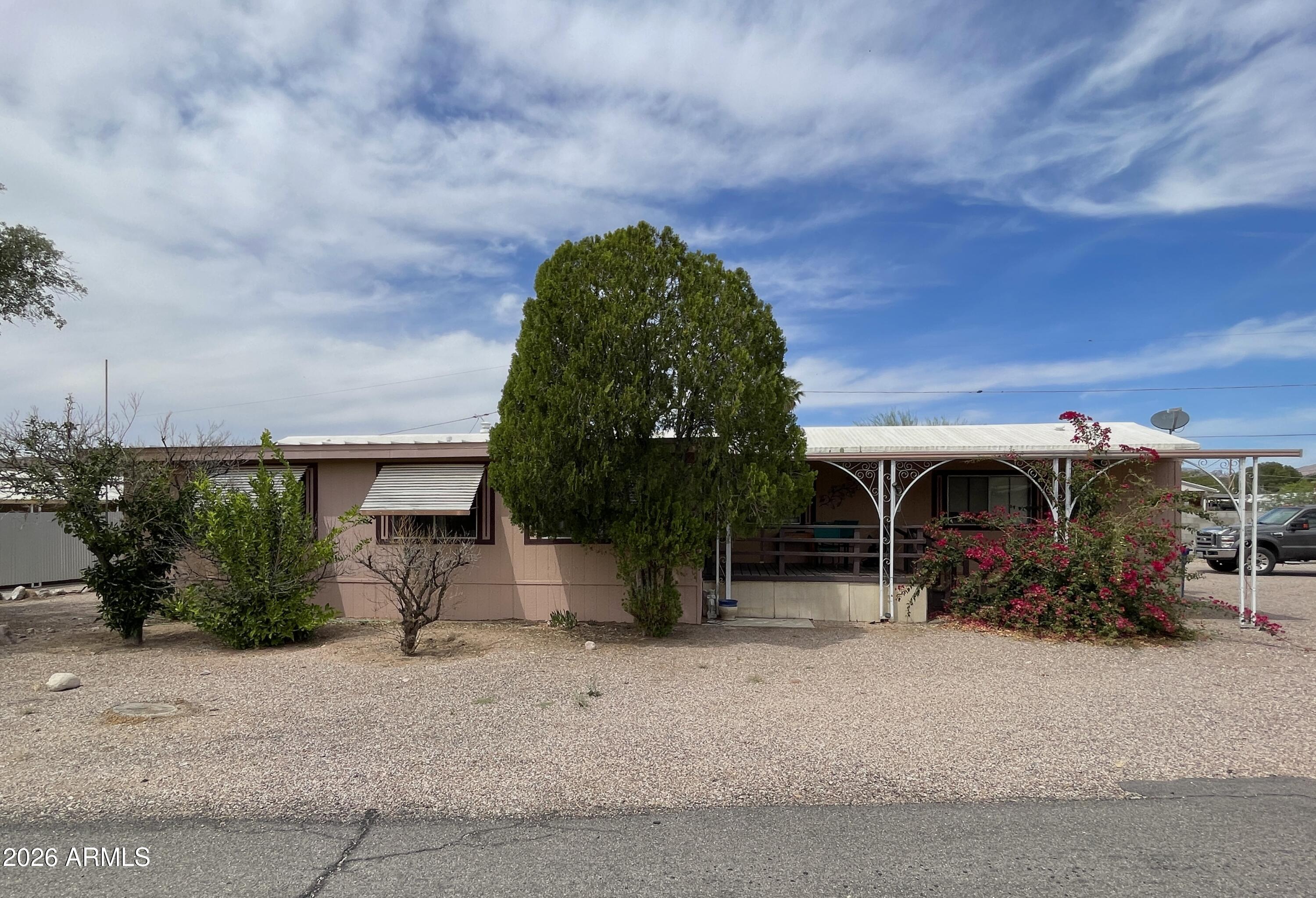 Escape the hustle--no HOA, no heavy traffic, just peace and open space. This 2-bedroom, 2-bath home is tucked into a quiet community featuring a golf course and direct access to miles of scenic trails leading into the Superstition Mountains and Tonto National Forest. 
Situated on a generously sized lot there is plenty of room for RV parking, ATVs, golf carts, and all your outdoor toys--plus ample space to host friends and family. Convenient access from both the street and alley makes parking easy and flexible.
The mostly furnished home provides privacy, with the guest bedroom and bath on one side and the primary suite on the other. The kitchen includes a dedicated pantry for added storage, while the expansive living room offers versatility space for a home office or media area