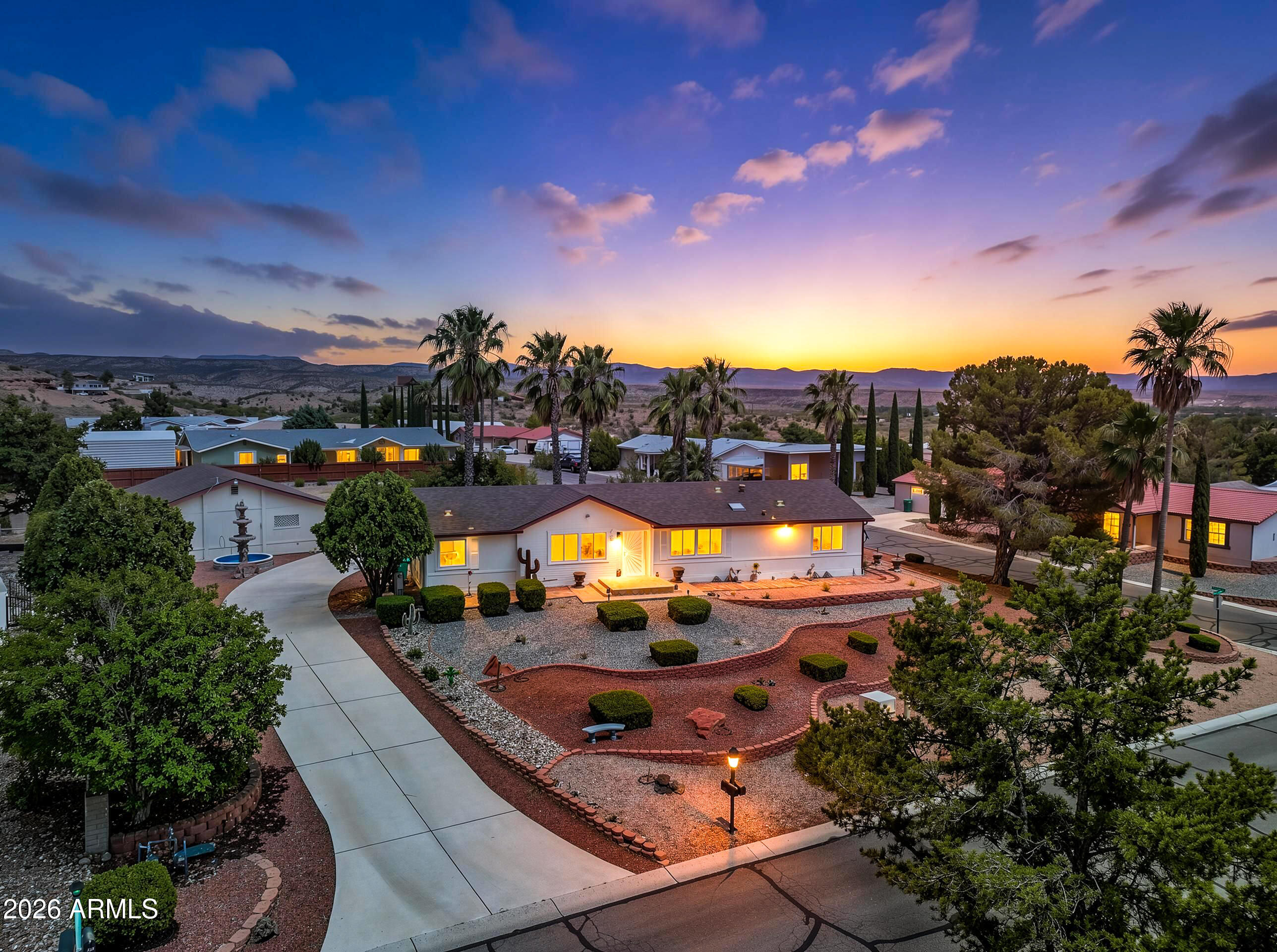 Palm trees, beautiful sunsets, and the soothing sound of custom terracotta fountains create a peaceful setting at this unique Mingus Shadows home. Situated on an elevated, nearly half-acre corner lot, this former premier model offers lush, low-maintenance landscaping, fruit trees, and no HOA or leased land. The thoughtfully designed floor plan features a newer screened-in patio, custom front window screens, and a newer gas range and hood vent. New carpet installed in bed rooms in 2025. The detached garage offers space for parking, storage, or a workshop. Additional updates include garage ventilation, fluorescent lighting, and blackout curtains throughout. Enjoy stunning sunsets and the peaceful charm of this special property.