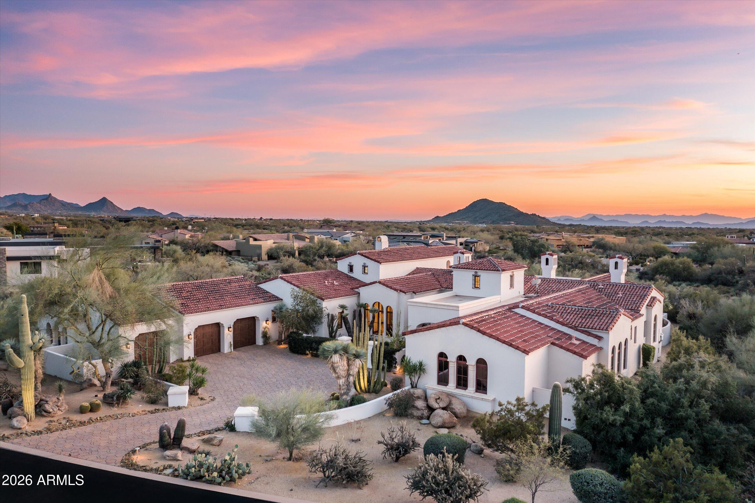 Crafted by the builder Platinum Companies in the prestigious guard-gated community of Whisper Rock Estates, this stunning residence offers an open, light-filled floor plan. The private primary suite serves as a true retreat, featuring a cozy fireplace, direct access to the backyard patio, and dual baths with separate closets. An oversized office/media room--complete with a privacy curtain, wet bar, and hidden access to the fourth-bay garage--also functions seamlessly as a home theater. Custom designer finishes include white oak wood flooring, dramatic beamed ceilings, built-in wine storage, slab countertops, hand-painted tile accents, and elite appliances throughout. A spacious upstairs guest retreat offers a kitchenette and private patio with sweeping southern views. The south-facing backyard is ideal for year-round enjoyment, highlighted by the heated pool and spa with a stone waterfall feature, and a built-in barbecue for effortless outdoor entertaining.