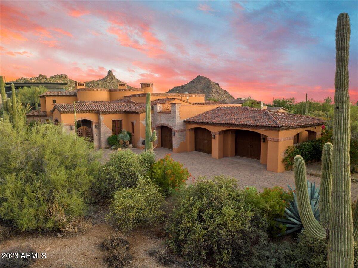 Nestled within the prestigious Estancia Golf Club, this captivating Old World Spanish-style residence is a testament to timeless elegance and architectural craftmanship.  With 3 bedrooms ensuite, plus an additional bedroom, or two offices, this home is a haven for those seeking classic charm and breathtaking natural beauty. Interior spaces are adorned with exquisite slate stone and wood plank flooring, brick feature walls and beamed ceiling detail lending an air of rustic authenticity. The heart of the residence is the spacious living area, with a centerpiece fireplace, adjacent to wet bar and wine cellar. The primary bedroom suite is a private retreat with cozy fireplace, exercise room and spa-like bathroom. Outdoor living spaces are remarkable with multiple seating areas and fireplaces with panoramic views of Pinnacle Peak and breathtaking sunsets.  Enveloped in lush landscaping, the home provides privacy and tranquility.
