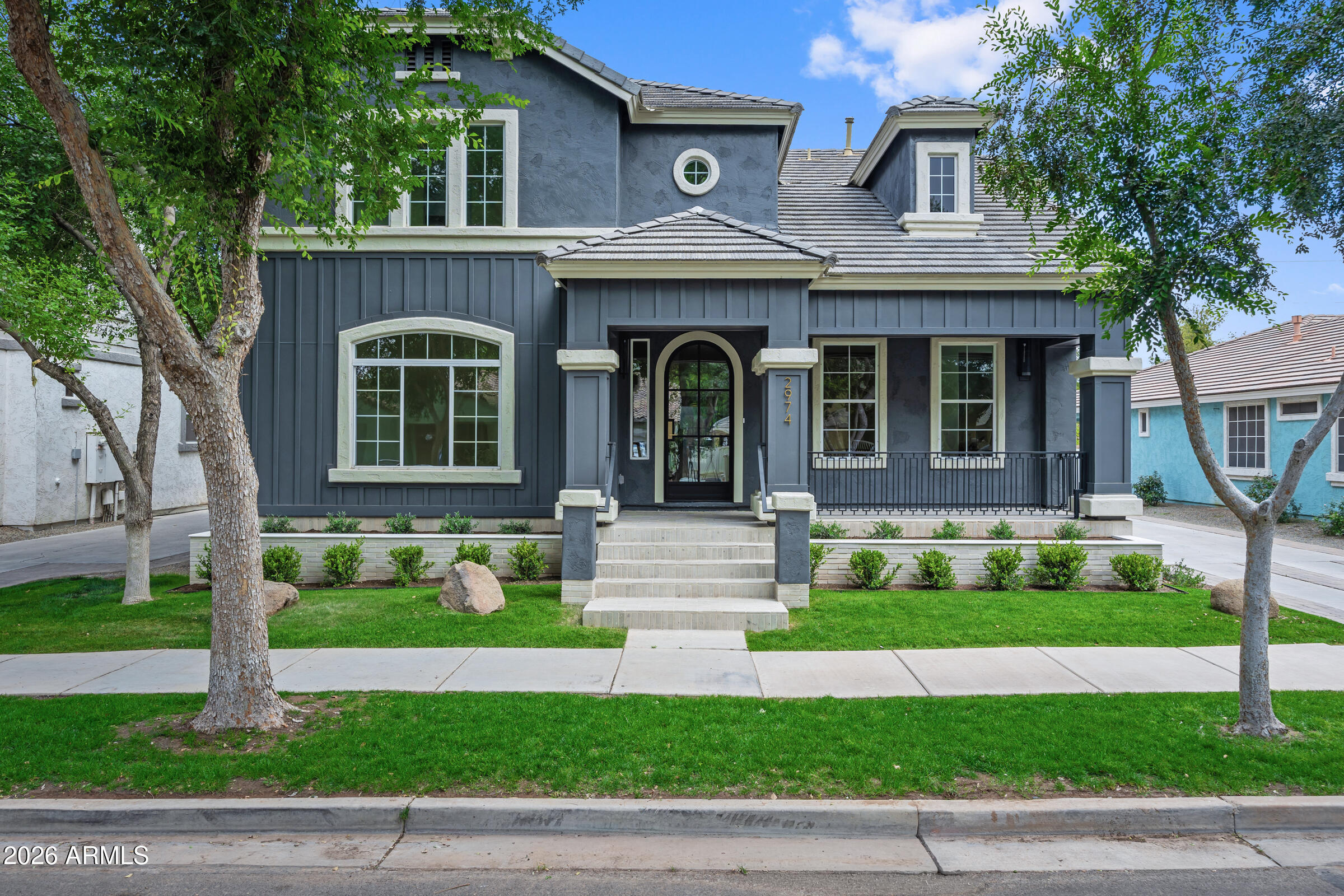 A complete ground-up reinvention in the heart of Agritopia. This 5,979 square foot estate has been taken down to the studs and rebuilt with a level of design intent rarely seen at this price point in the East Valley. Six bedrooms, six bathrooms, a finished basement, and a fully detached poolside casita combine to create one of the most thoughtfully reimagined homes ever offered in the community.

The exterior sets the tone, deep charcoal board-and-batten siding, crisp white trim, a covered front porch with iron railings, and a custom arched iron-and-glass front door that anchors the elevation. Mature trees and a manicured front lawn create instant curb appeal in a neighborhood where homes rarely look this intentional from the street.
Step inside to wide-plank European white oak hardwood floors that flow throughout the main level. Custom steel-frame interior glass doors, geometric iron stair railings, and designer lighting carry through every transition. The floor plan is open without sacrificing definition, formal sightlines from the entry, a great room built for entertaining, and a chef's kitchen that anchors the entire main floor.

The kitchen is the centerpiece. Two oversized islands provide prep space, casual seating, and storage. The 48-inch professional dual-fuel gas range with brass accents is paired with a matching custom hood, double wall ovens, panel-ready built-in refrigeration, and a dedicated beverage center. Light rift-cut oak cabinetry surrounds the cook zone while matte black cabinetry on the islands grounds the space. Stone countertops, a vertical-stack tile backsplash, and a walk-in pantry round out a kitchen that genuinely performs at the level its appearance suggests.
A wall of multi-panel sliding glass doors opens the great room directly to the covered patio and resort backyard, blurring the line between indoor and outdoor living and pulling Arizona's best months straight into the home.

The primary suite is a true retreat. A spa-caliber bathroom features floor-to-ceiling marble slab walls in the walk-in shower, a freestanding fluted soaking tub, dual fluted oak floating vanities with marble countertops, designer alabaster sconces, statement pendants, brass plumbing fixtures, and a custom geometric tile floor. The oversized custom closet system is built for two, open hanging, drawer banks, integrated lighting, and a clean, designed-to-last finish.

Every secondary bathroom in this home is its own design moment  no two are alike. Black marble slab walls with brass-accented trough sinks. Hand-laid art deco geometric floor tile. Fluted walnut vanities with white marble counters. Alabaster pill-shaped sconces. Glossy black vertical stacked tile shower walls with marble mosaic floors. Designer mirrors, designer fixtures, designer lighting throughout. The level of customization in the secondary baths is what separates this home from anything else on the market in Gilbert at this price point.

The dual stacked LG washer and dryer setup creates four total laundry units in a single dedicated room, wrapped in floor-to-ceiling matte black cabinetry over a black-and-white basket-weave geometric tile floor. A practical solution for a six-bedroom home, executed as a design feature rather than an afterthought.
The finished basement adds significant living space with stone tile flooring, black five-panel interior doors, oversized windows, and direct access to a covered patio. Flexible enough to function as a media room, secondary great room, home gym, or guest wing.
The fully detached casita is a property within a property. Private exterior entrance, stone tile floors, oversized sliders that open directly to the pool deck, full bedroom, and walk-in closet. Ideal for multigenerational living, long-term guests, a private home office, or rental income potential.

The backyard delivers a true resort experience. Private pebble-finish pool and spa with a natural rock waterfall and built-in wading shelf, synthetic turf for low-maintenance green space, and paver hardscape connecting the main home to the casita. The covered patio off the great room provides shaded outdoor dining and lounge space year-round.

Located in Agritopia, one of Gilbert's most walkable and sought-after communities. Steps from Joe's Farm Grill, Barnone, the community gardens and orchards, neighborhood parks, tennis courts, and pickleball. Top-rated schools, easy freeway access, and a true sense of place that defines the Agritopia lifestyle.
A complete renovation of this caliber, on a lot that includes a private pool and a detached casita, in this community, at this price, is a rare combination. Schedule your private showing.