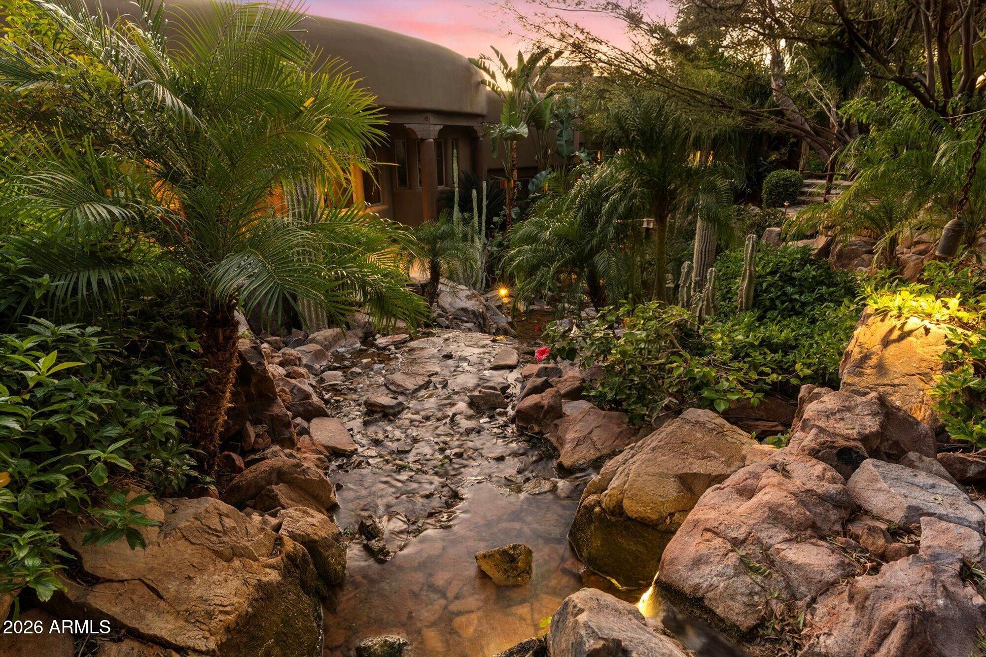 Hand-carved into the very mountain it rests upon, this extraordinary estate is more than a home--it is a livable work of art. Every element has been thoughtfully sculpted, from the hand-carved doors to the sweeping, curvilinear walls and ceilings, culminating in the striking wagon wheel ceiling that serves as a true architectural centerpiece. Rich in detail and artistry, the residence offers an immersive experience that continually reveals new layers of craftsmanship and design. Nearly every aspect of the home has been thoughtfully touched, enhanced, or updated, seamlessly blending modern comfort with timeless architectural significance. Set within the exclusive and aptly named Lost Canyon, this is one of the most private properties in the area--yet just minutes from Scottsdale's private airport and the city's premier dining, shopping, and entertainment. Encompassing approximately 14 acres, the estate is surrounded by the breathtaking expanse of the McDowell Sonoran Preserve, offering over 30,000 acres of protected desert landscape and more than 180 miles of scenic trails.

The outdoor living experience rivals that of a world-class resort--lush, immersive, and designed to transport you. Meandering pathways wind through the estate, following a tranquil stream and leading to a series of enchanting destinations. Towering natural surroundings and layered landscaping create a rare, Costa Rican-inspired atmosphere in the heart of the desert, where every turn feels like a secluded escape.
Throughout the grounds, ten fireplaces are thoughtfully placed, casting a warm glow that enhances the ambiance from intimate evenings to large-scale gatherings. From a secluded reading retreat perched at the upper reaches of the property, to a romantic grotto adorned with intricate stonework, every space invites exploration. Grassy play areas, swings, and a private golf chipping area further enhance the estate's park-like setting.

Entertaining is elevated to an art form with a rustic outdoor culinary pavilion, ideal for family cookouts and unforgettable evenings under the stars. Multiple seating areas, dramatic natural backdrops, and the soft flicker of firelight create an atmosphere that is both inviting and unforgettable--capturing the essence of a private luxury resort.

Inside, the home continues to impress with uncompromising quality and bespoke finishes. Venetian plaster walls, reclaimed oak flooring, and hand-carved mesquite doors speak to the level of craftsmanship found throughout. The kitchen is both functional and inspiring, with architectural detailing and panoramic views that make it a space you'll never want to leave.

Designed for luxurious living and exceptional privacy, the residence offers an extraordinary collection of private suites, each thoughtfully designed as its own secluded retreat. The primary suite is a sanctuary unto itself--a sprawling two-room escape featuring a dedicated sitting area, two expansive walk-in closets, a private sauna, breathtaking views, and multiple patios that create a serene indoor-outdoor experience. Complementing the primary retreat are three additional luxury en suite suites, each offering exceptional privacy, distinctive views, and private outdoor patios. One suite is designed as a casita-style retreat, complete with its own separate entrance, private living area, and kitchenette--ideal for extended guests, multigenerational living, or private staff quarters. The remaining two suites are equally well-appointed, featuring its own kitchenette and the ability to be closed off from the main residence, creating fully self-contained private quarters. Every suite throughout the home is uniquely positioned to capture stunning vistas and provide a peaceful connection to the surrounding landscape.
A temperature-controlled wine tasting room showcases exquisite stonework, providing a setting as refined as the collection it houses. The primary office is equally remarkable, with custom millwork and thoughtful design that foster both creativity and focus.
Possible future expansion offers a rare opportunity to further elevate the estate, with additional buildable space that may allow for a separate structure designed for private living quarters, a guest residence,  as well as the addition of a multi-car garage. Preliminary conceptual renderings have already been prepared and can be shared with prospective buyers


This majestic mountain retreat is a rare offering--where art, architecture, and nature converge to create a home that lives like a private resort and feels as extraordinary as it looks.
