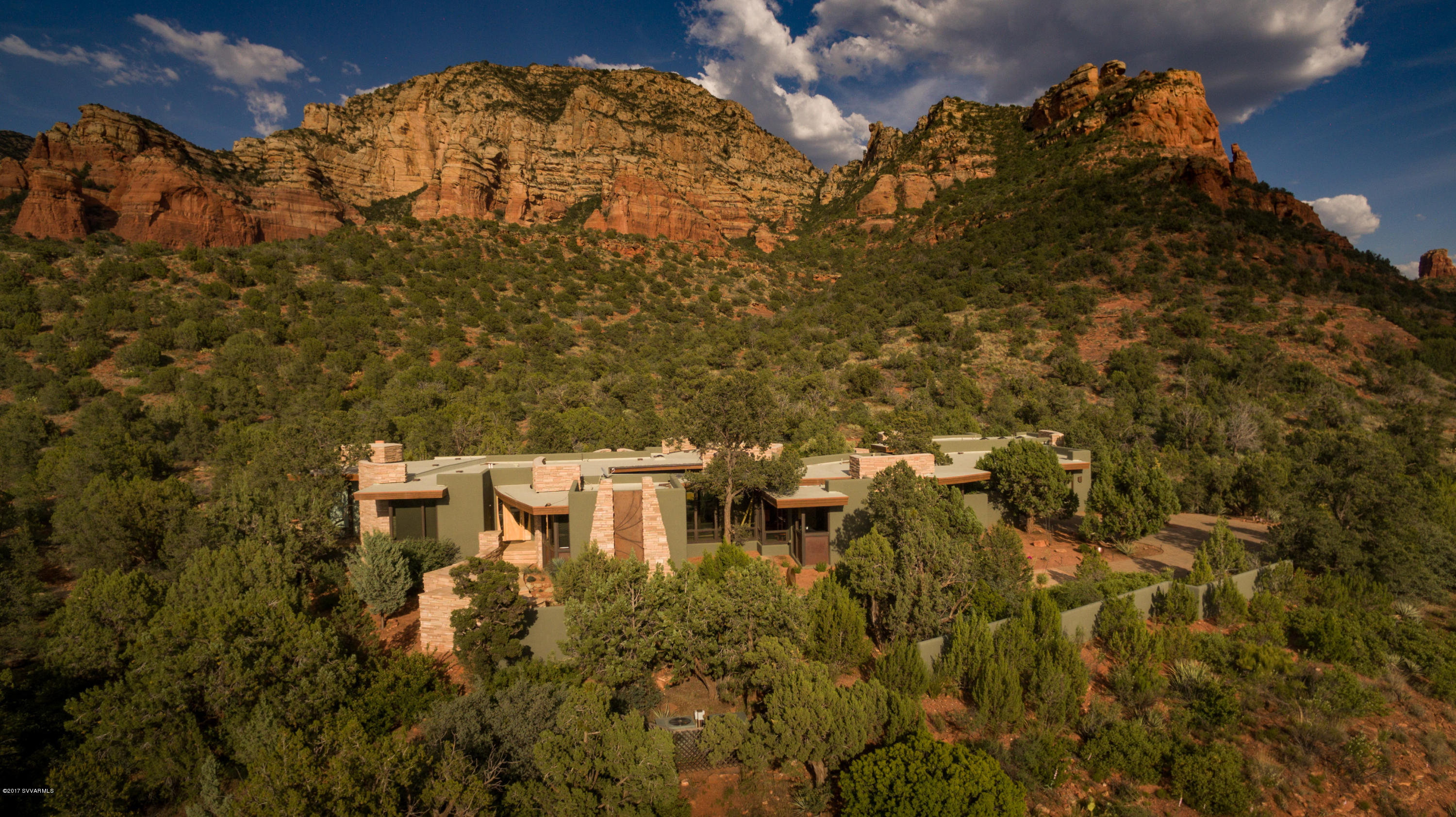 This Design Group contemporary masterpiece is truly an extraordinary residence. It’s the ultimate architectural work of art, drawing together extravagant elements of stone, glass, wood, metal, and water in a brilliant composition that exemplifies the best of its gorgeous U.S. National Forest setting – and, in turn, blends in with it organically. It’s a marvelously livable home that embraces you in luxurious comfort as well as beauty. It’s Sedona gracious living at its best, where the elegant interior flows seamlessly to the magnificent outdoors. Inside, the exquisite design of the living room, dining room, chef’s kitchen, exercise room, study, and master bedroom suite epitomizes quality beyond expectation, complemented by stunning red rock views from every window. See the 3D Tour in Photos
An inner courtyard entices you to become one with nature while relaxing by the pool or enjoying a romantic alfresco dinner.  On the far side of the courtyard your family and friends will delight in the spacious and beautifully appointed guest casita. On the northern side of the two and half acre lot, we find a 1,200+ sq.ft. studio/guest house with additional living quarters, expandable garage space, and a versatile studio with its own separate driveway and gate. The entire property is surrounded by a privacy wall and fencing, with two custom metal entry gates to each garage. Inside, the compound feels like a world unto itself  - quiet, serene, and bathed in beauty.  Search as you might, you'll find no other home like it in Sedona: "This is the best house I've ever seen in Sedona." This comment from a veteran agent was enthusiastically echoed by the other members of the Sedona Luxury Real Estate Professionals present at a recent evaluative gathering at 1800 Dry Creek Road. This no exaggeration. Come experience this very special home.

Features and Amenities

TWO custom gated entries and driveways 
Paver and flagstone driveways, entries, and pathways
Garage space for SIX cars
Design Group Architects
Sedona Custom Homes (John Griffin) Builder - who says. "This home has the most exquisite design features and ultra high-end quality components of any home I've seen in Sedona."
"Smart home" capabilities with iPad
Tom Aderhold custom front door and light fixtures/glass work
Floor-to-ceiling windows
Birdseye maple cabinets and doors by Traditional Craftsmen/Brian Smutz master woodworker
AZ Flagstone and hardwood flooring
Italian tile master bath
Guest bath in West Wing has steam room.
Kitchen:  SubZero, Miele, Dacor
Custom media room
Private executive office
Exercise studio room
Custom water feature and stream in the Courtyard
Accordion panel glass doors that open for great indoor-outdoor living
Outdoor kitchen
Studio can also be a full guest house or car collector garage
Whole house Venmar air exchanger
All fireplaces are versatile - that is they are plumbed for gas, but have masonry chimneys and can burn wood if desired.